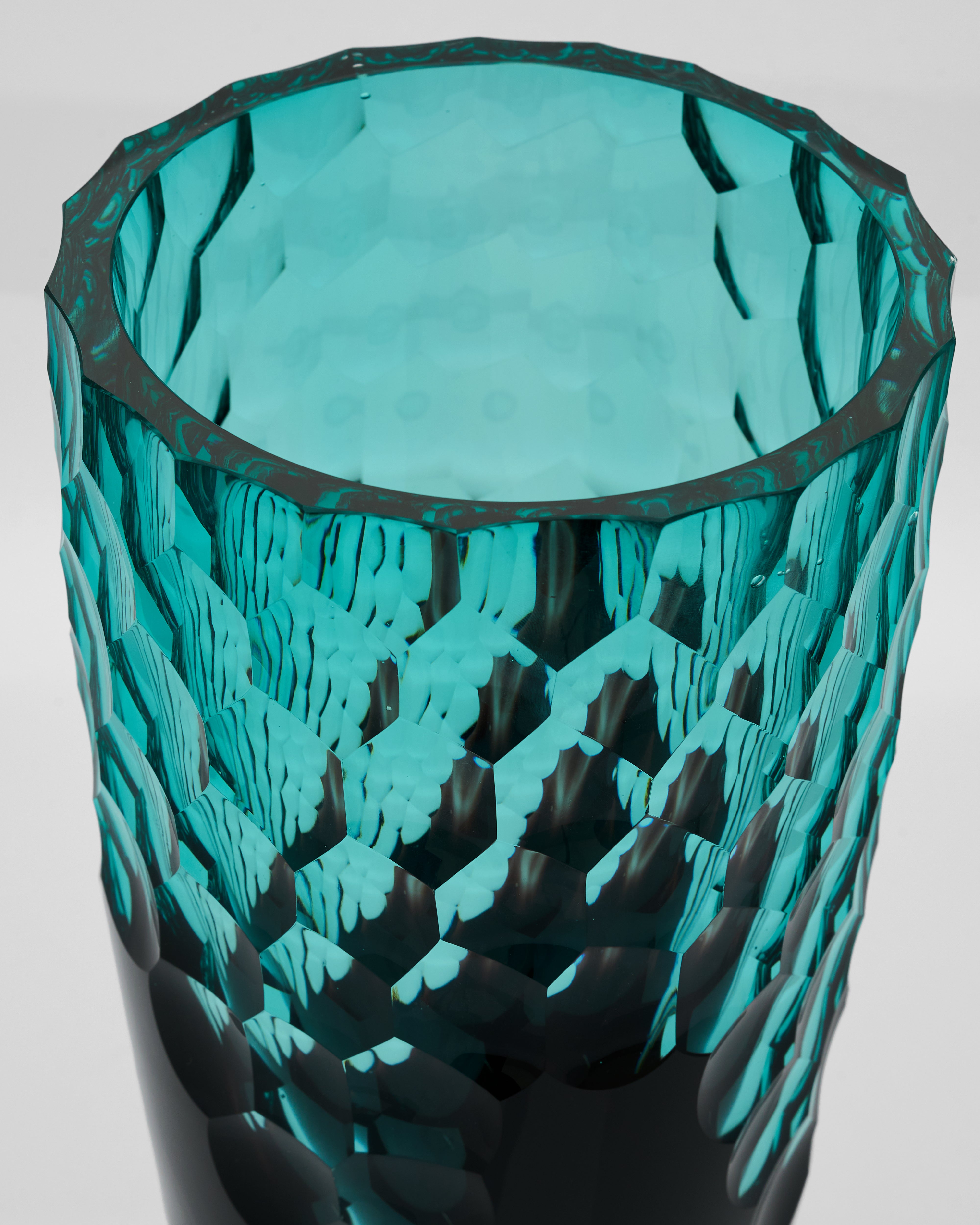 Teal glass vase with geometric pattern on a light gray background