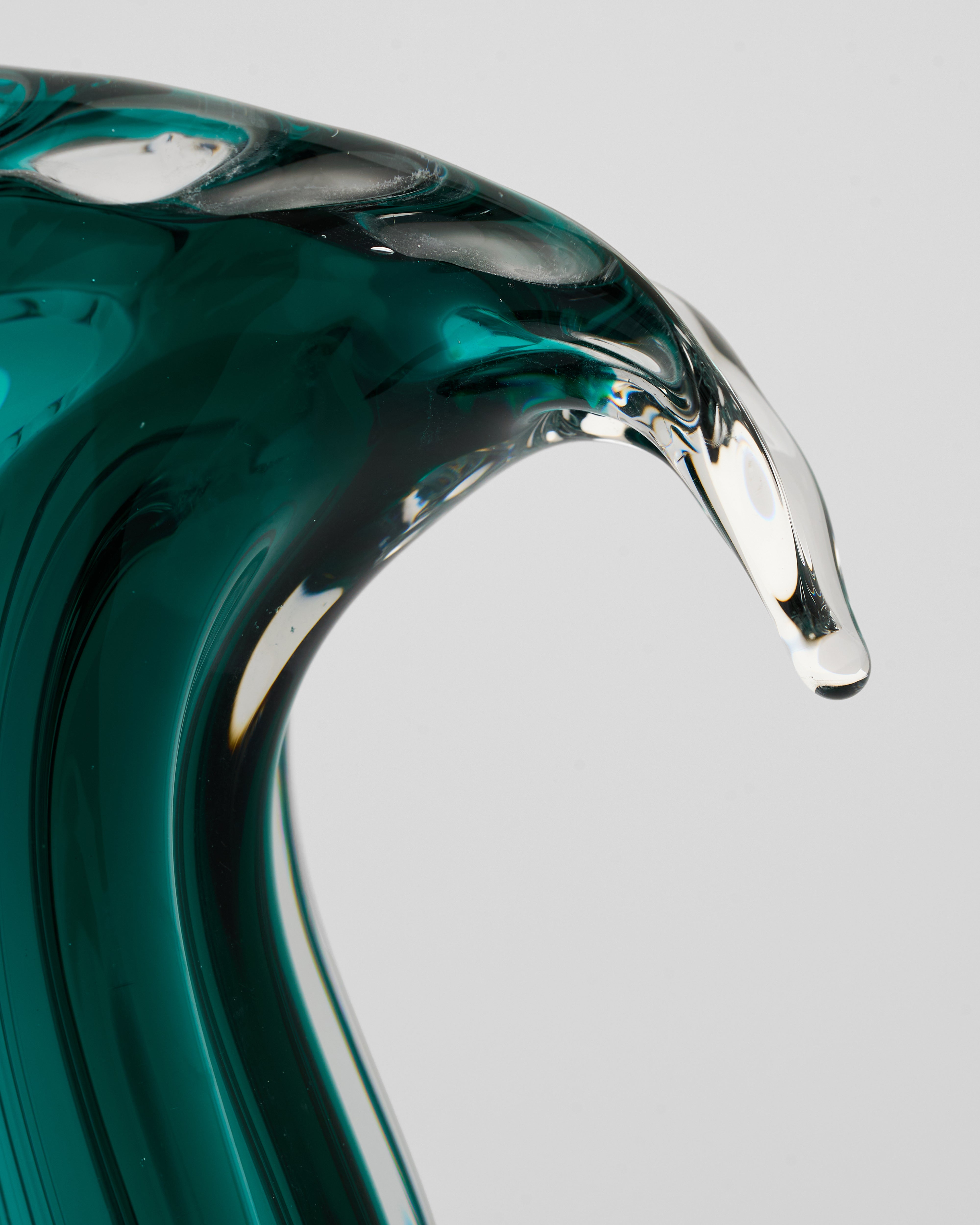 Teal glass vase with wavy design on a gray background