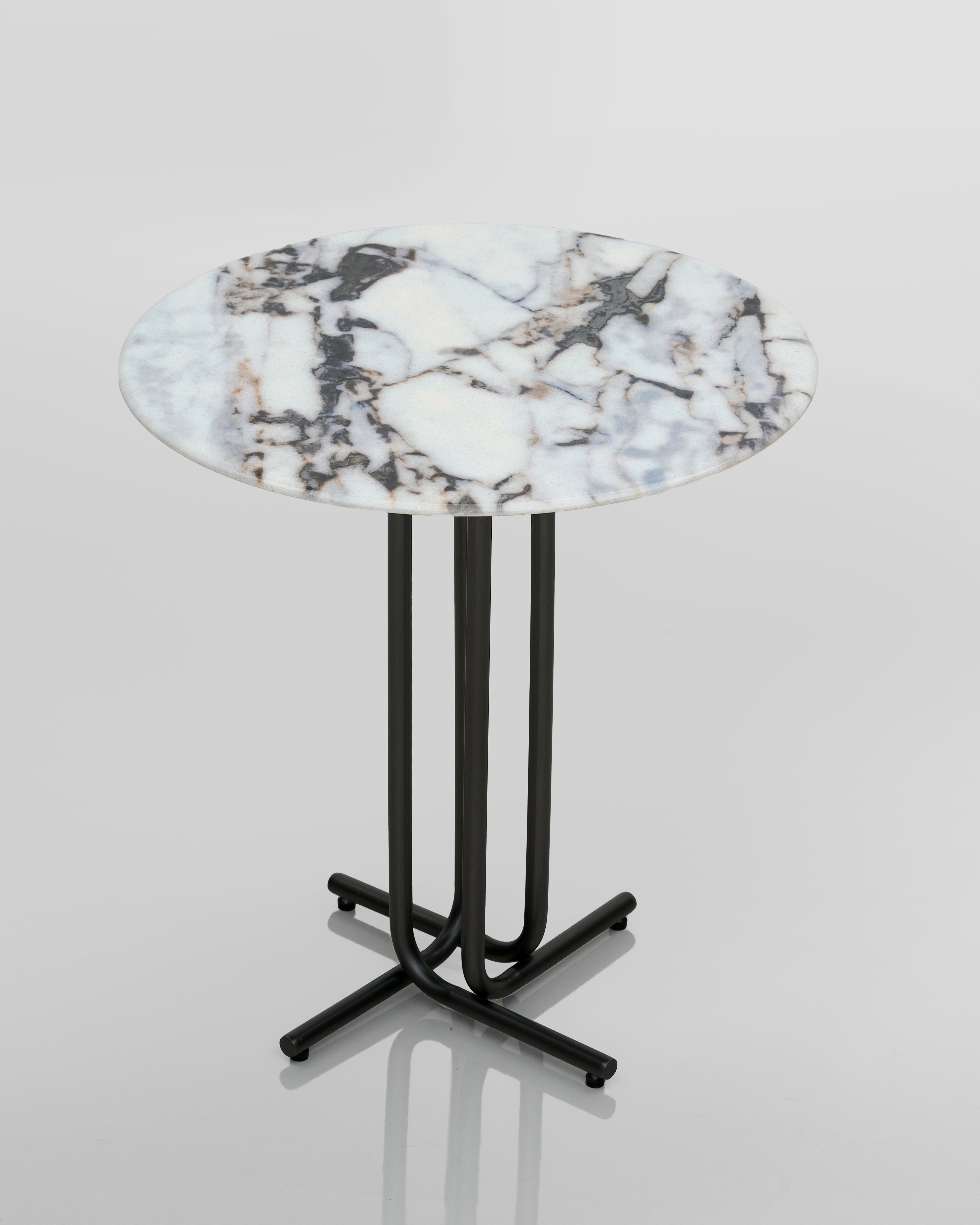 Round marble table with a black metal base on a light gray background