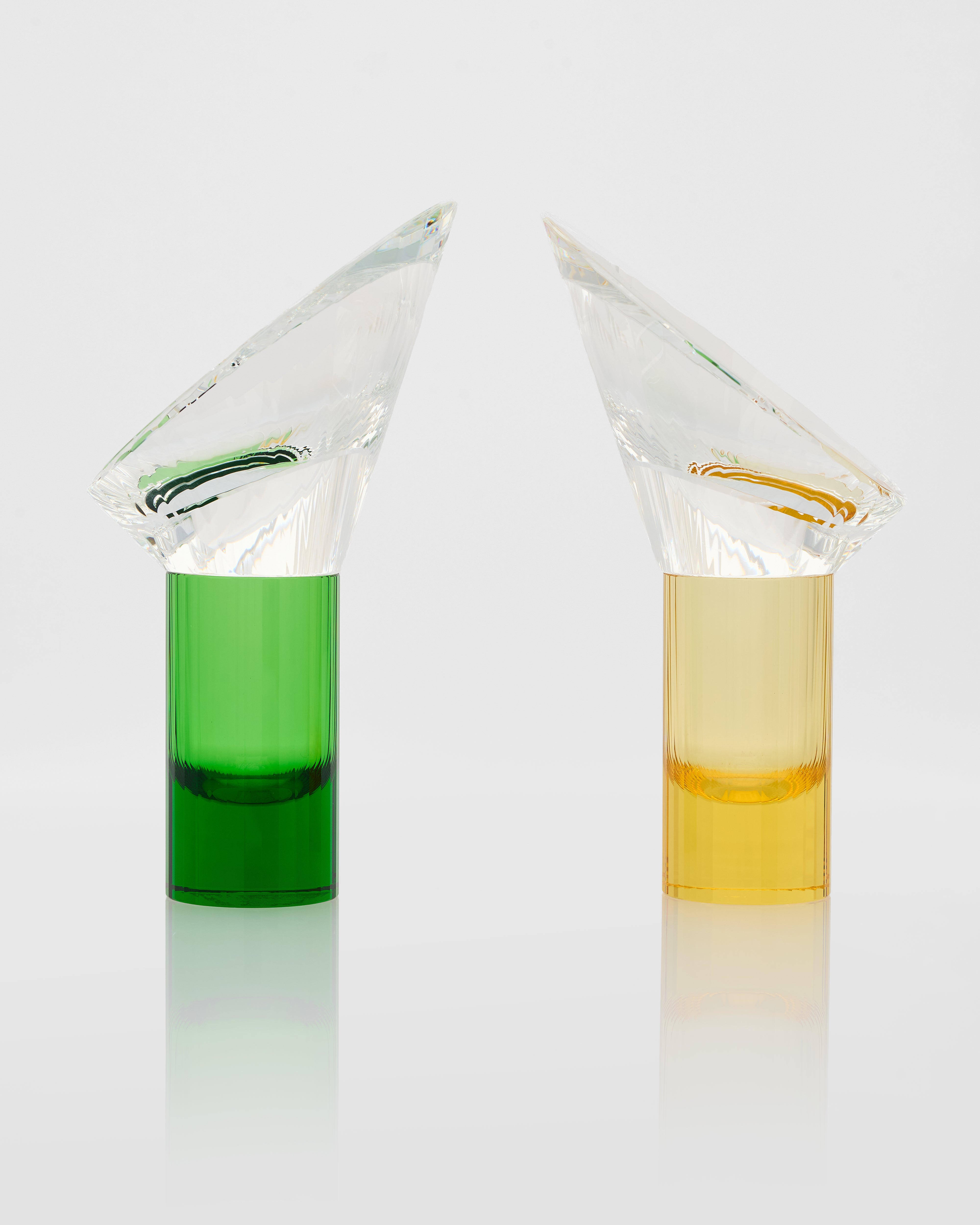 Two conical flasks with green and yellow liquids on a white background