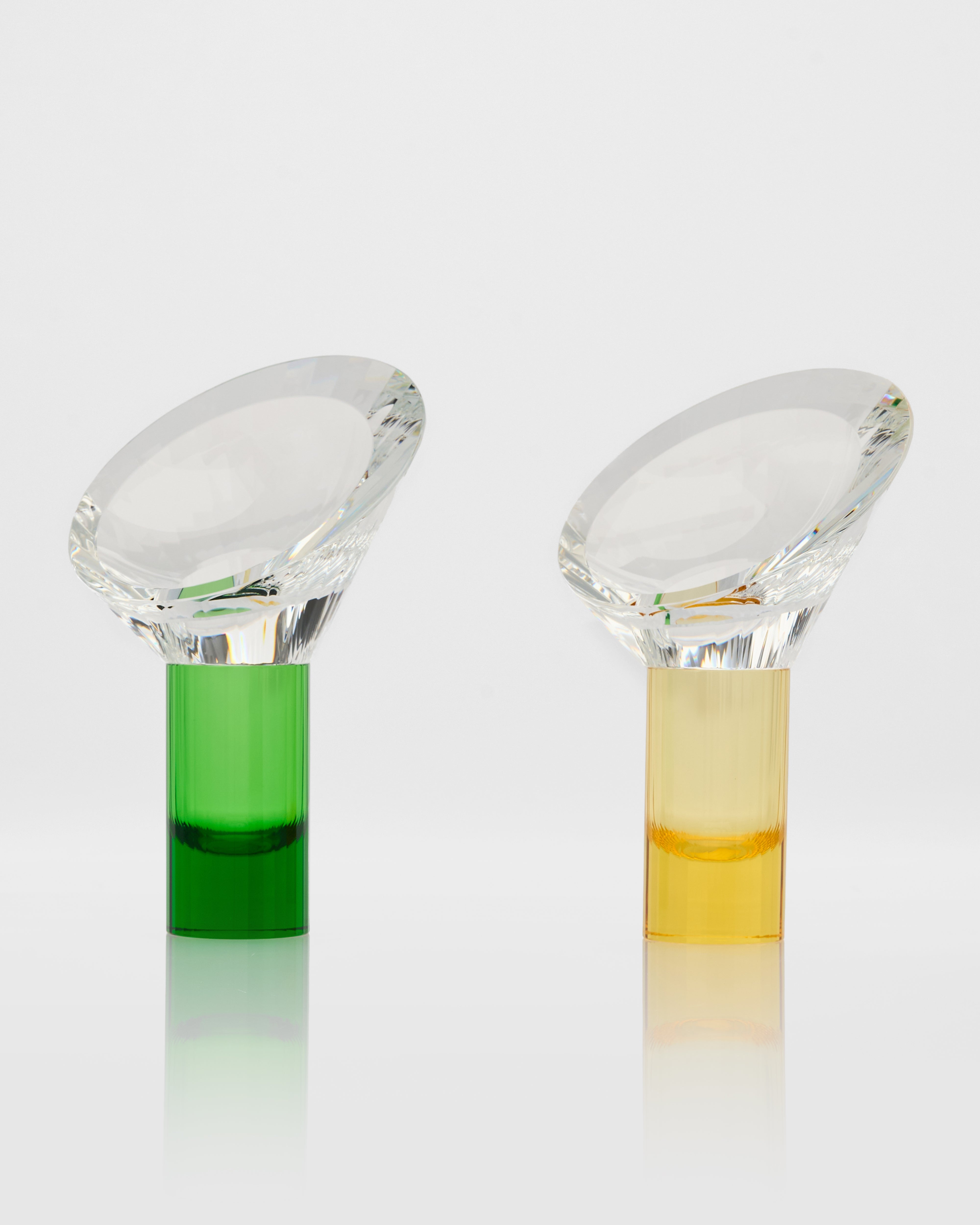 Two glass vials with green and yellow liquids on a white background