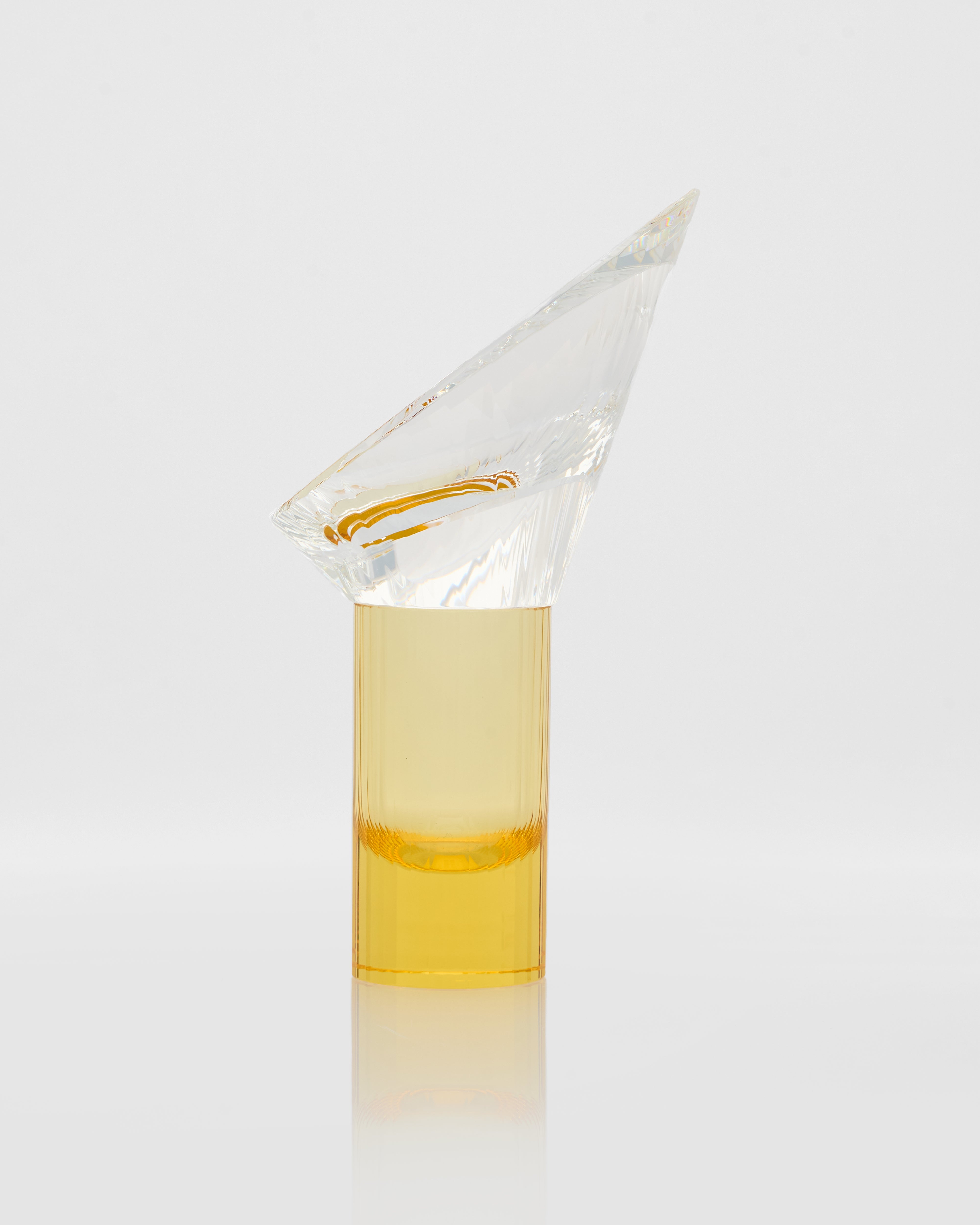 Clear glass container with a conical lid filled with a yellow liquid on a white background