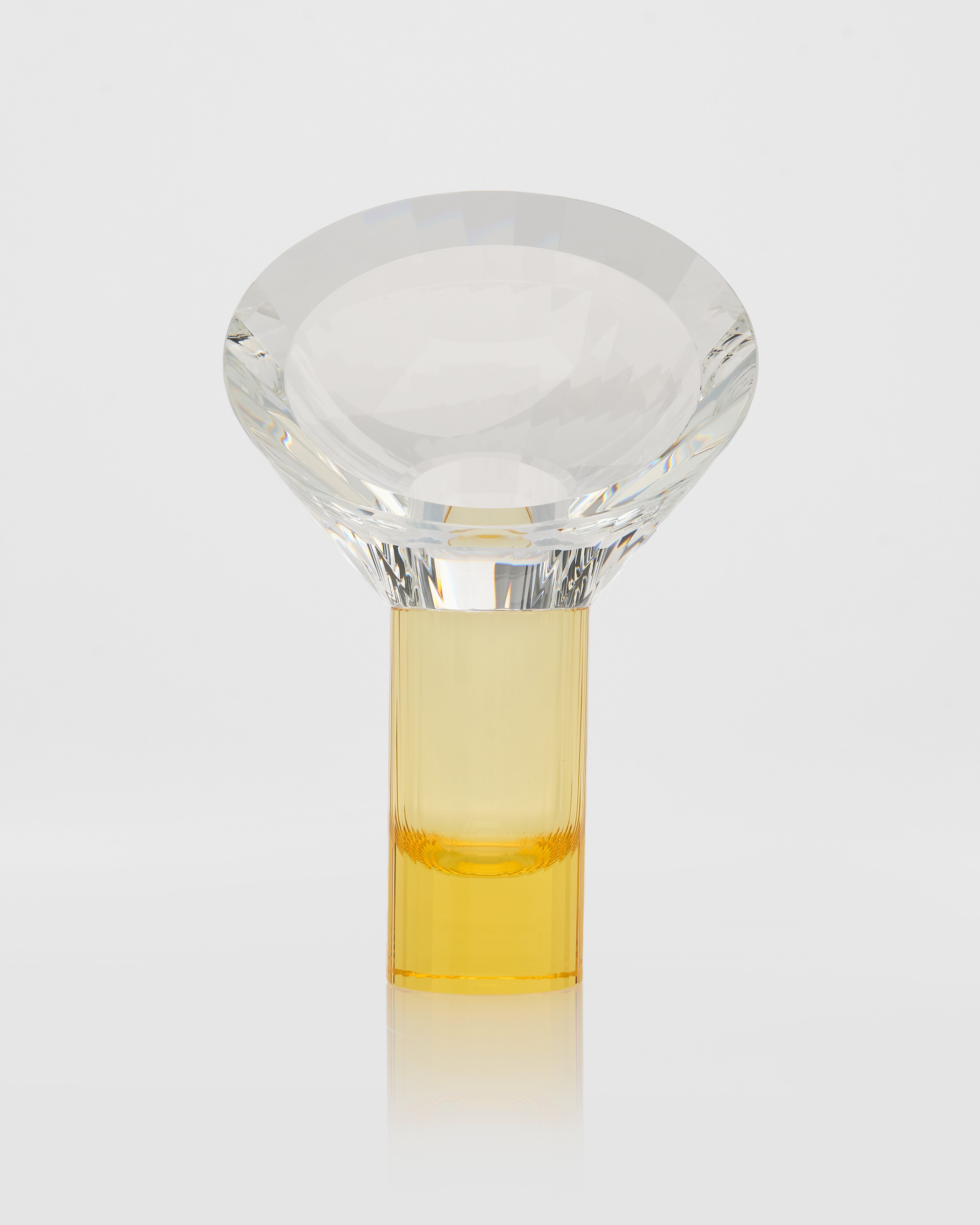 Clear glass object with a yellow liquid inside on a white background