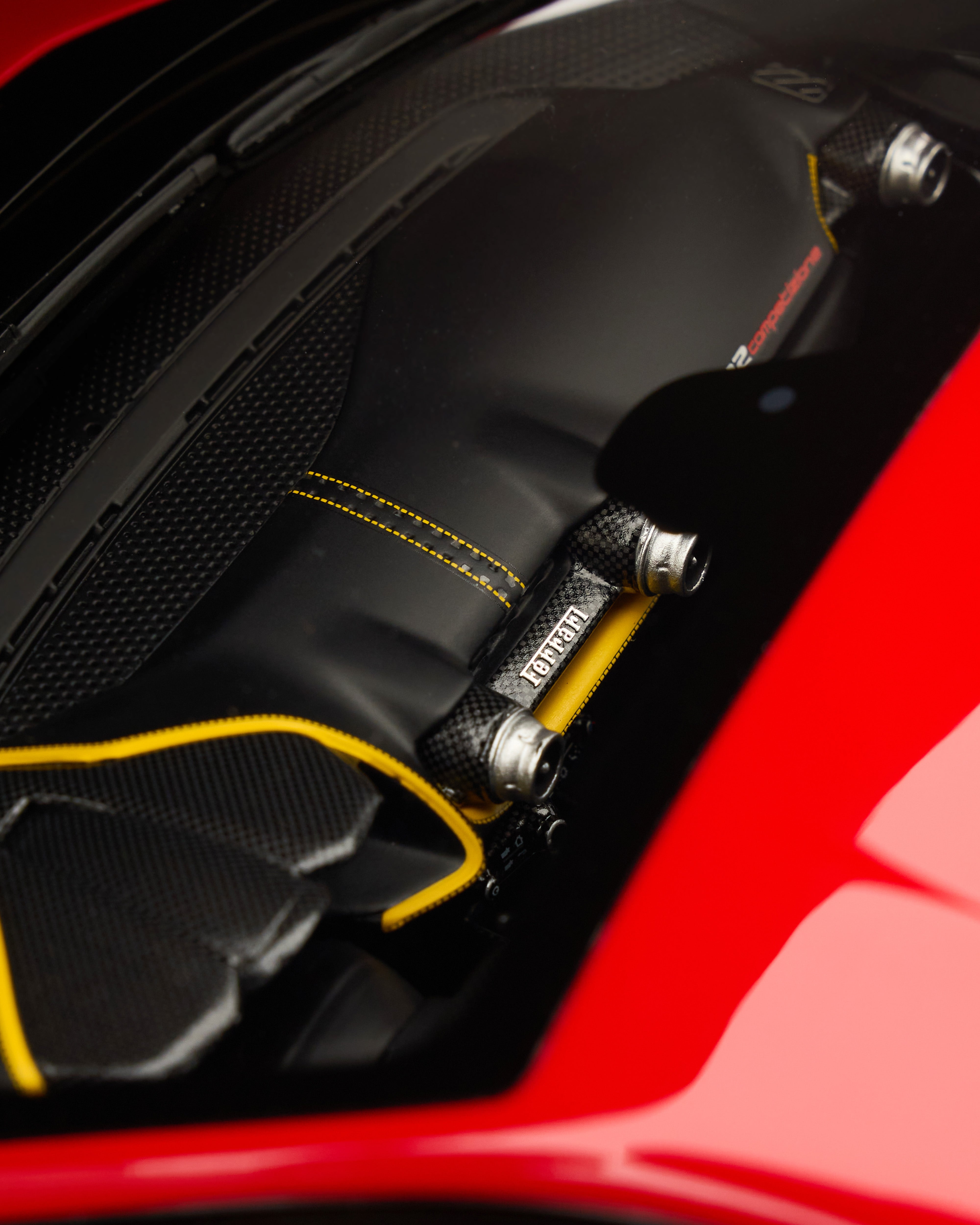 Close-up of a car's carbon fiber component with Ferrari logo on a red car background