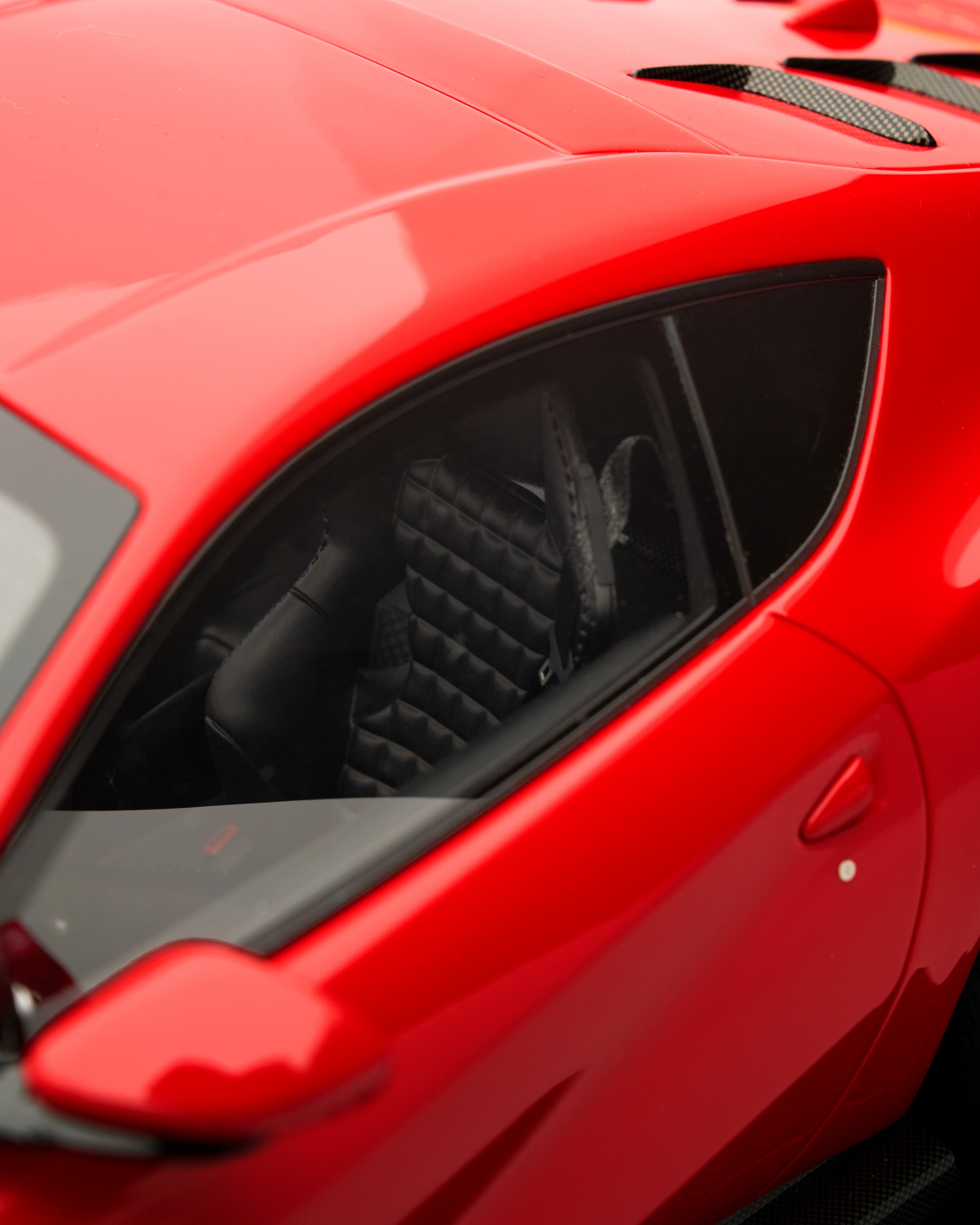 Close-up of a red car's side window with black interior.