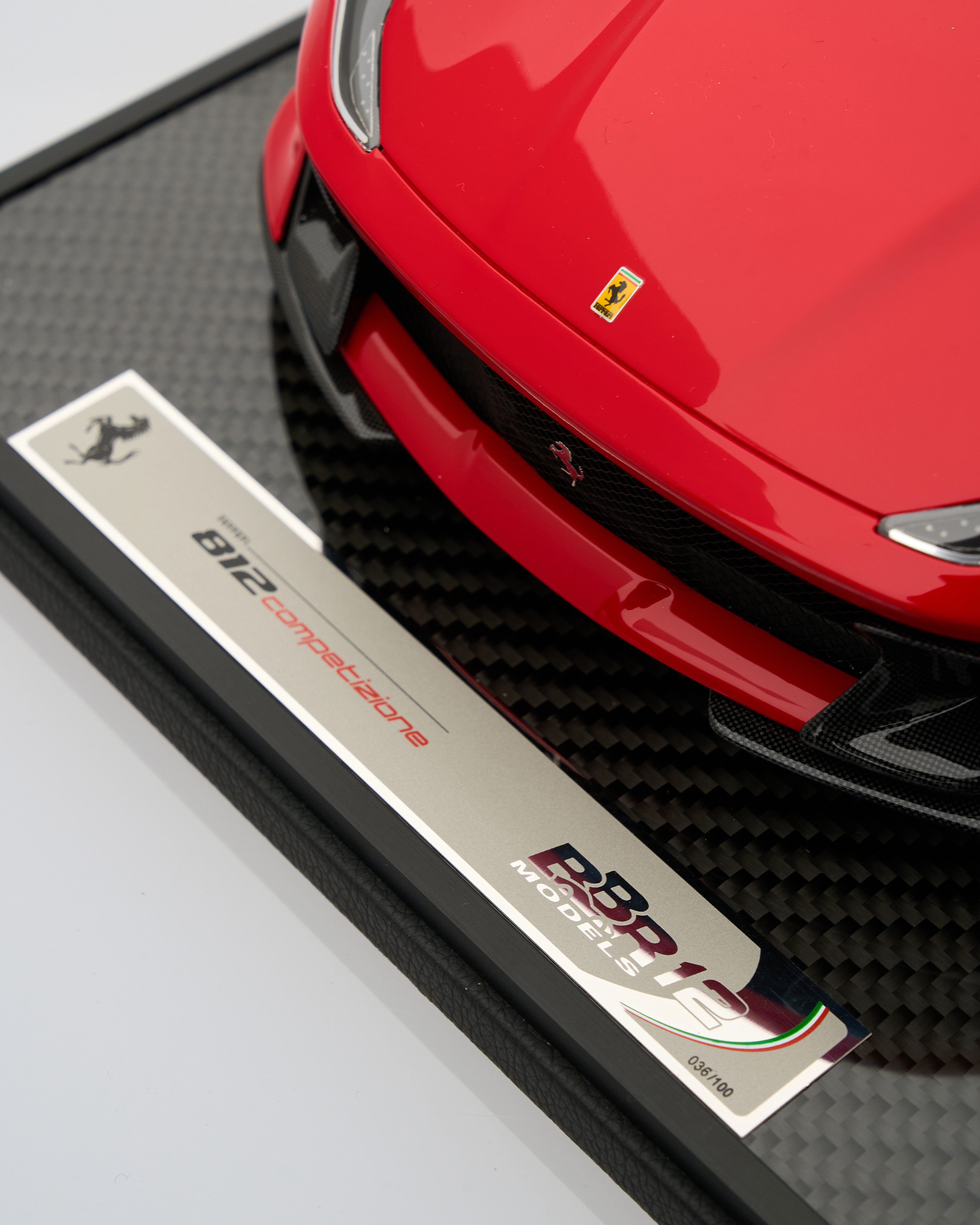 Red Ferrari car with a metallic plate displaying 'BBR' branding on a textured surface.