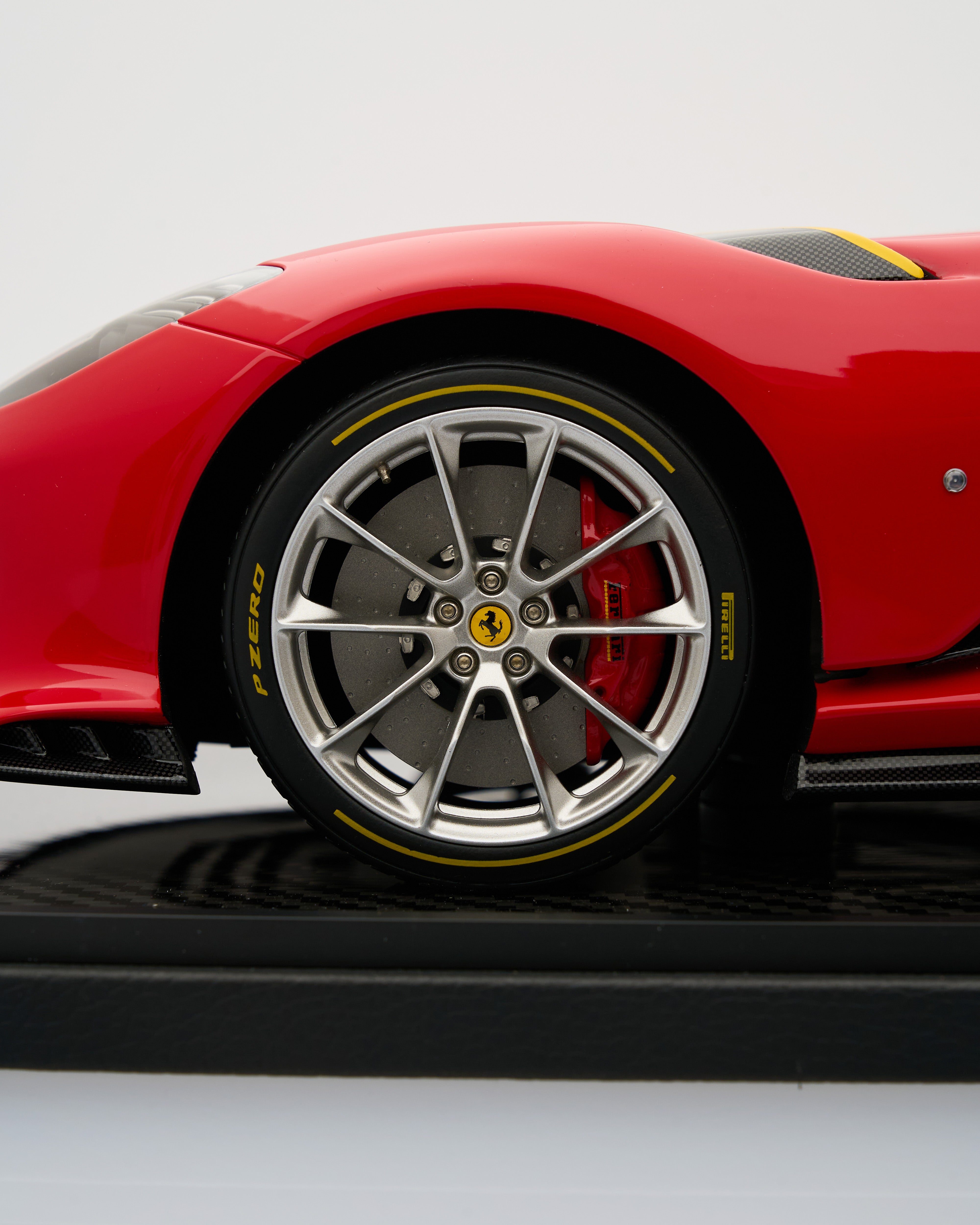 Close-up of a red Ferrari car wheel with visible branding on a light gray background