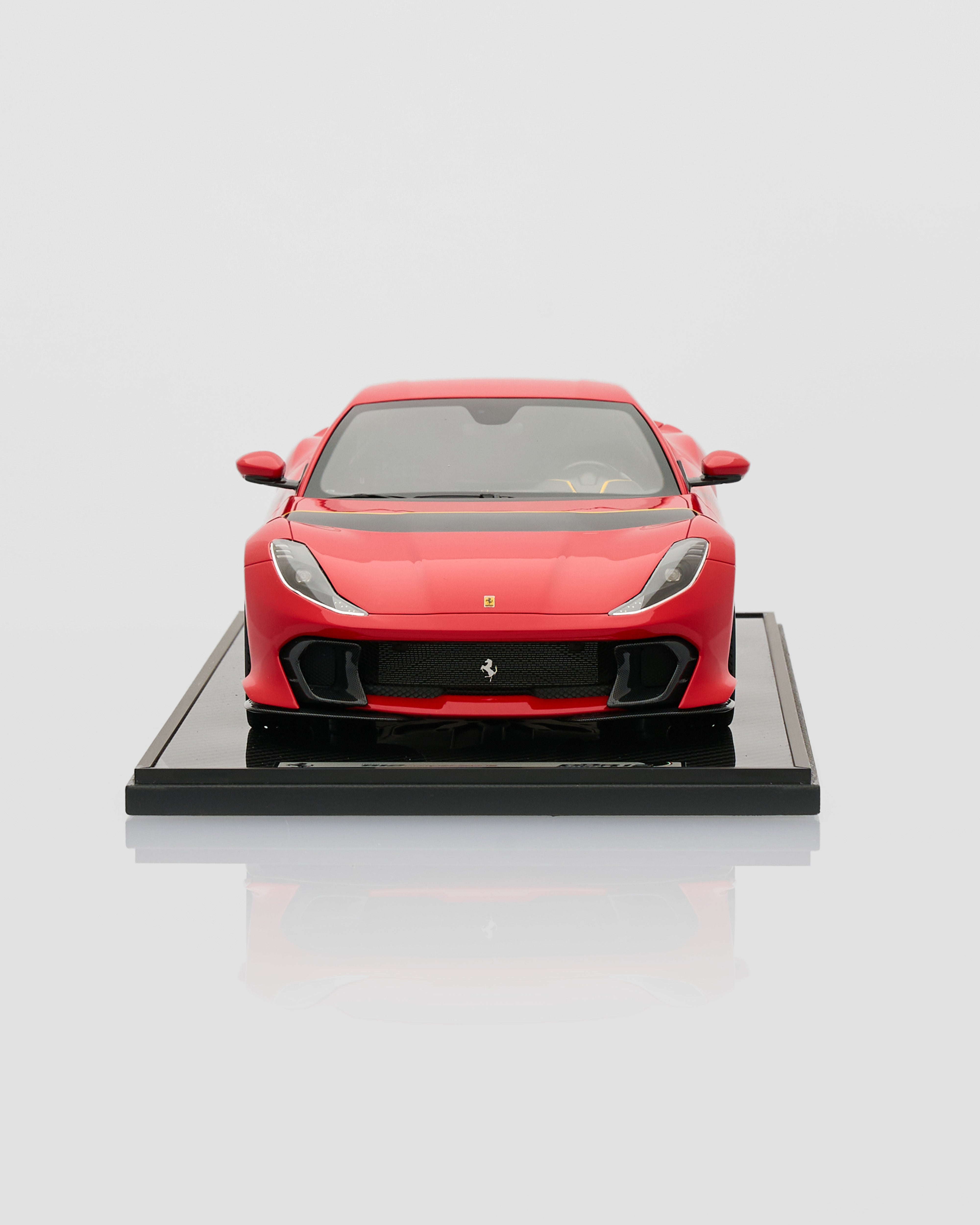 Red Ferrari car model on a reflective black platform with a light gray background