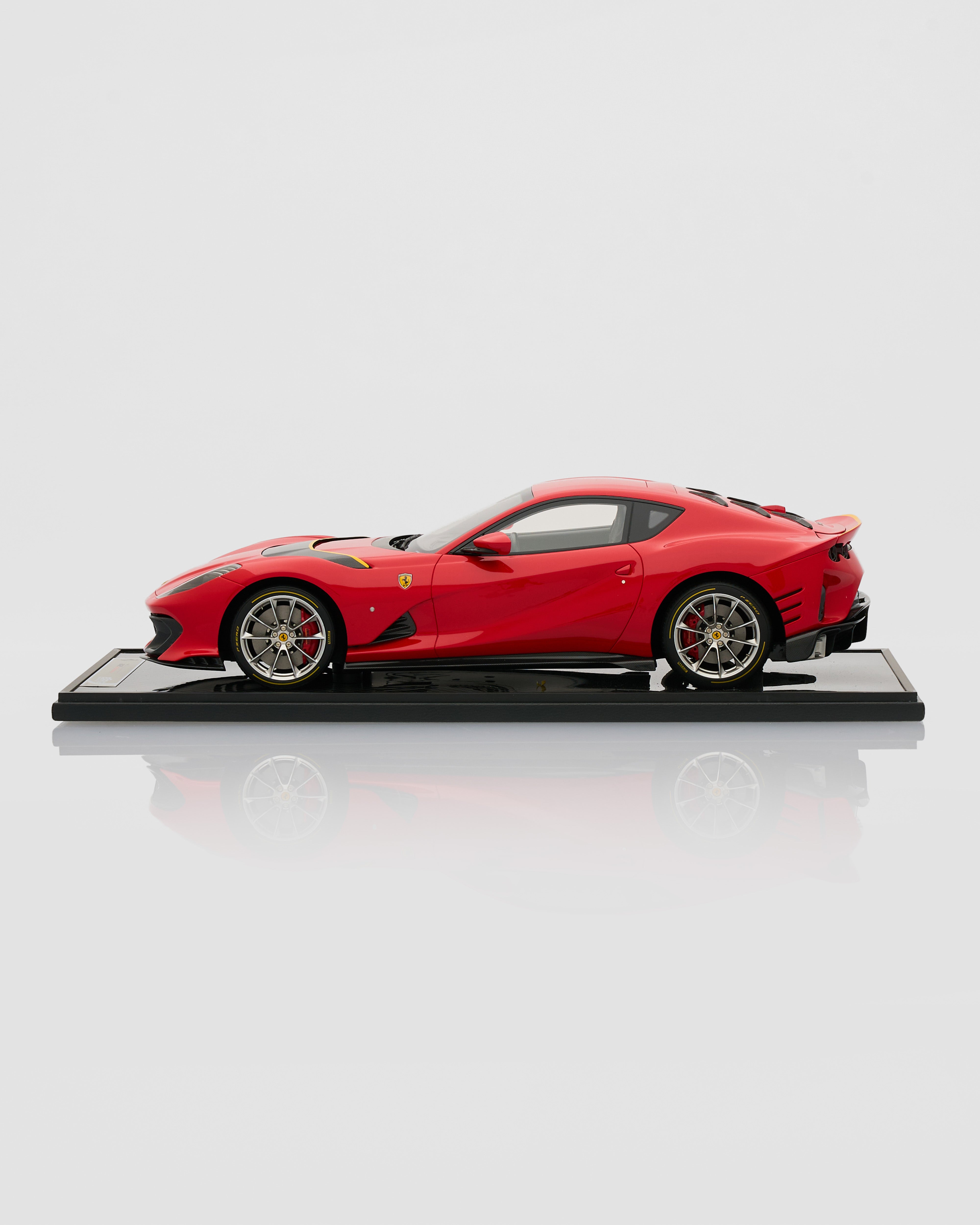 Red Ferrari model car on a white platform with a white background