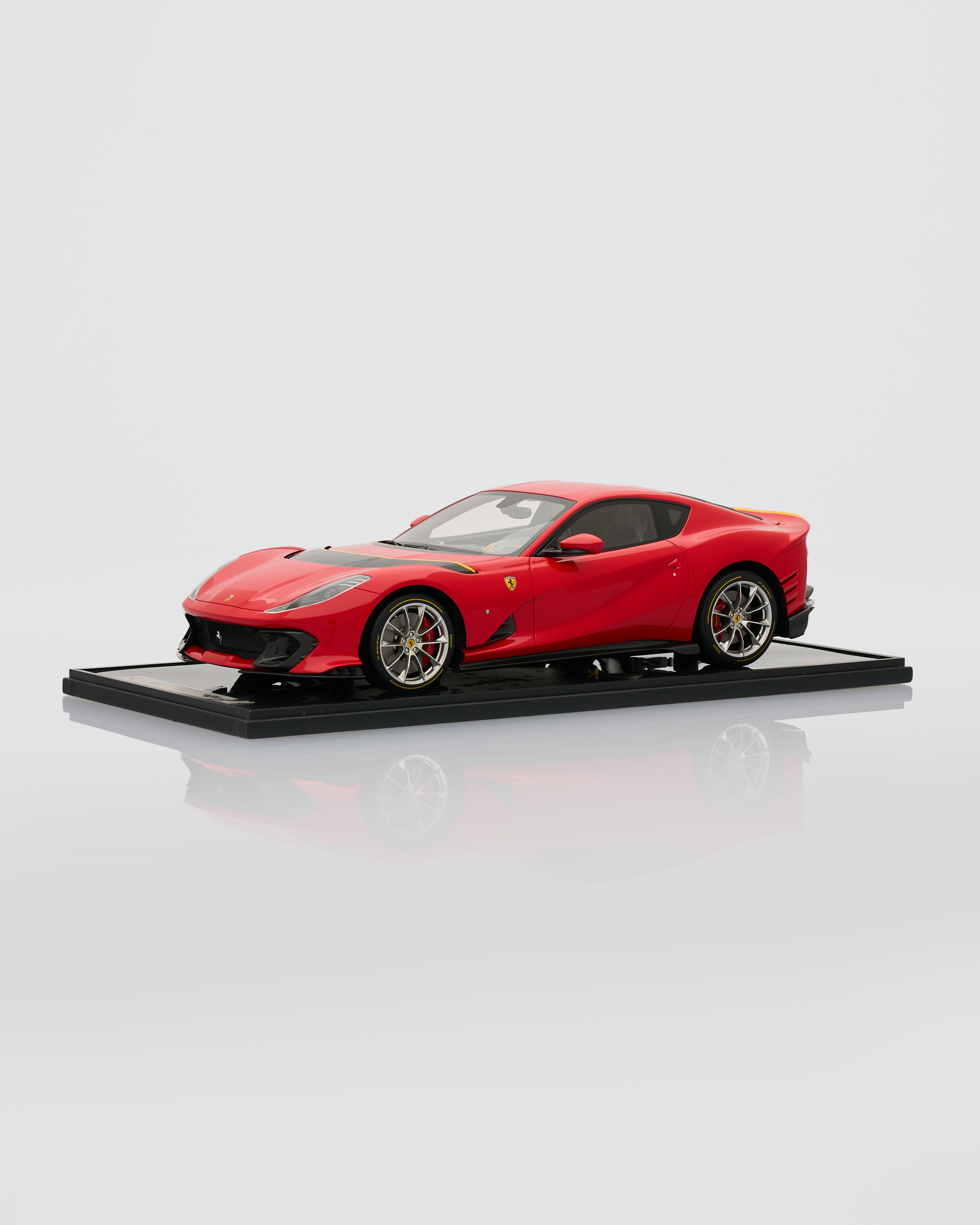 Red Ferrari model car on a black platform with a white background