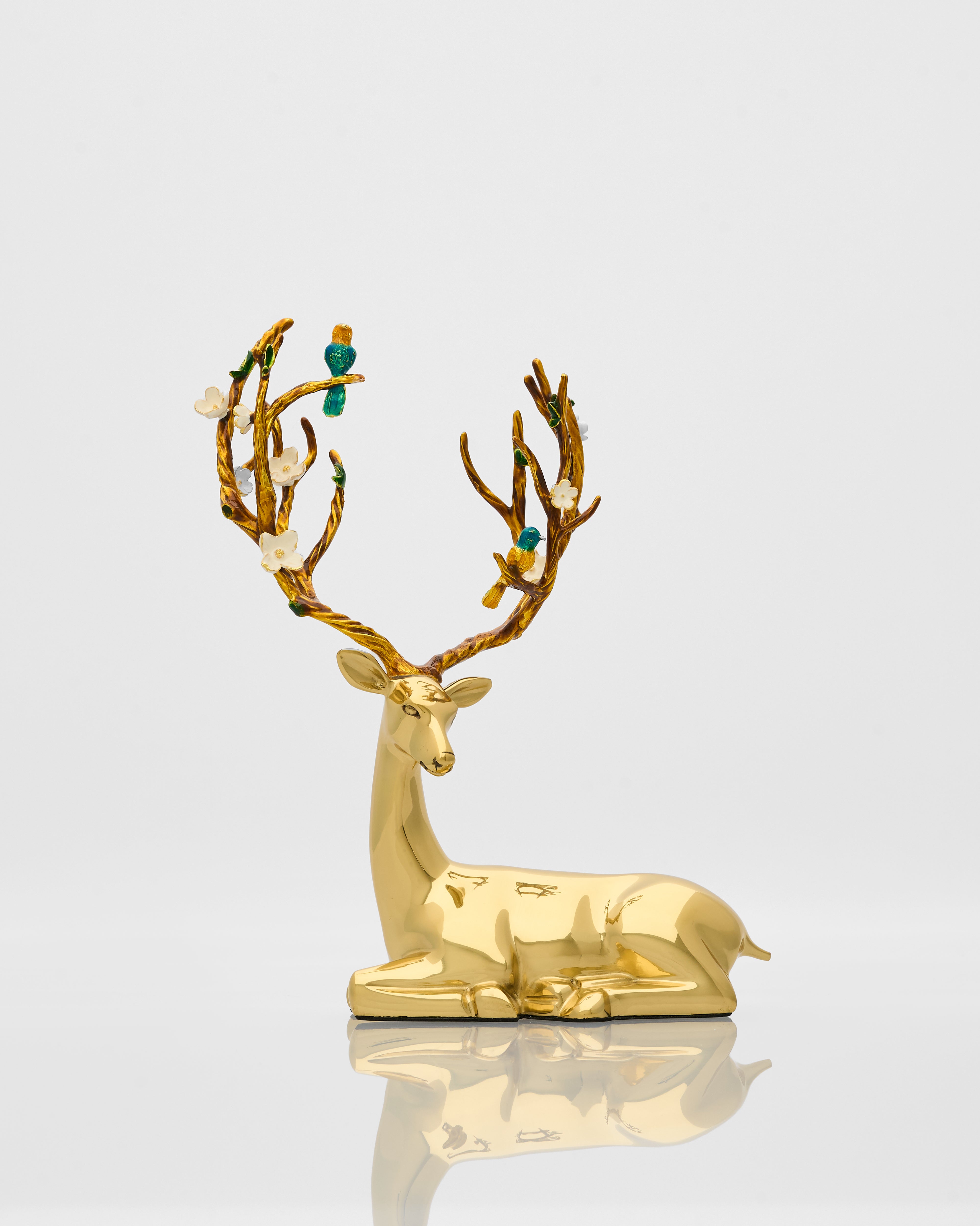 Gold deer figurine with decorative antlers on a reflective surface