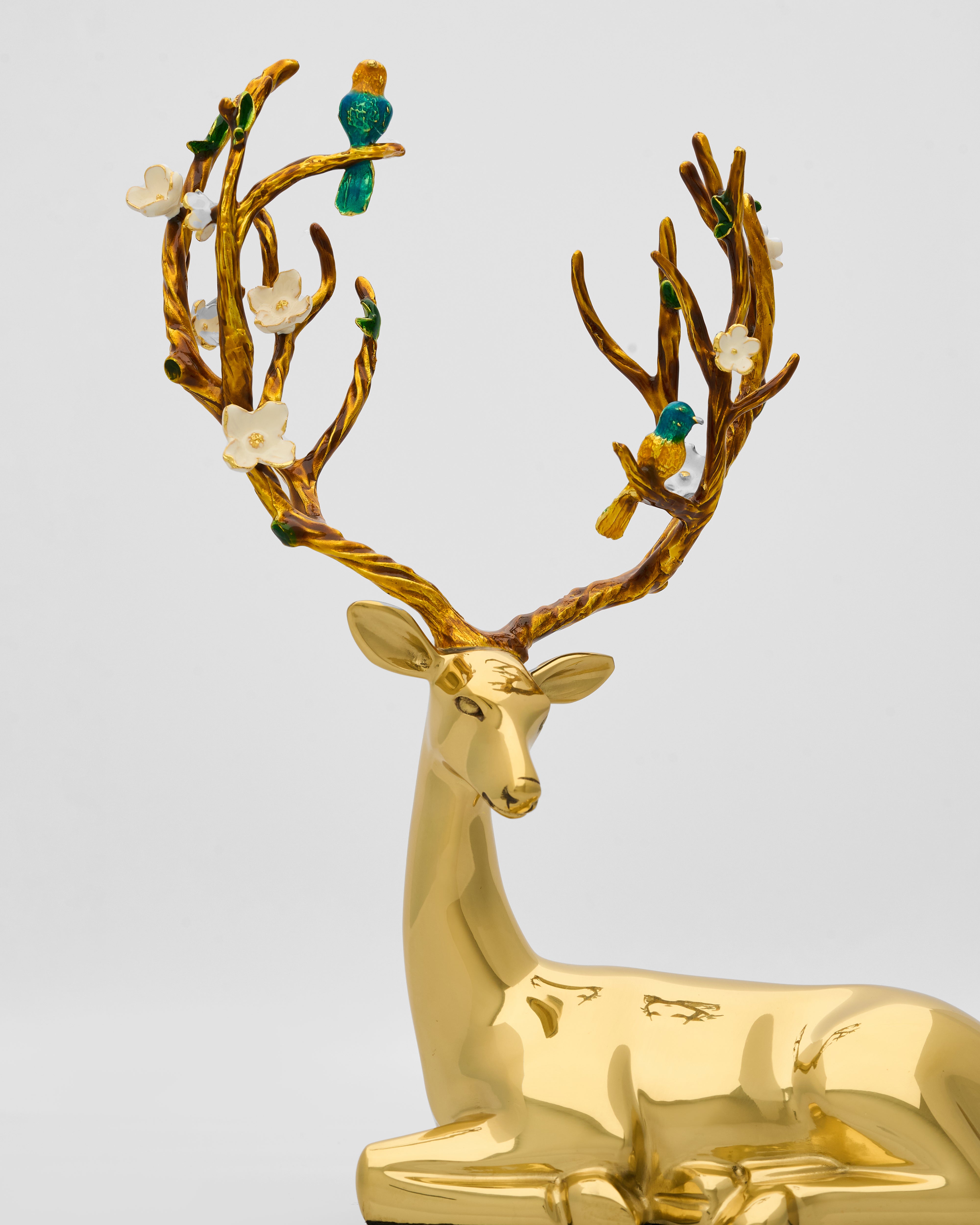 Gold deer figurine with decorative antlers on a light gray background