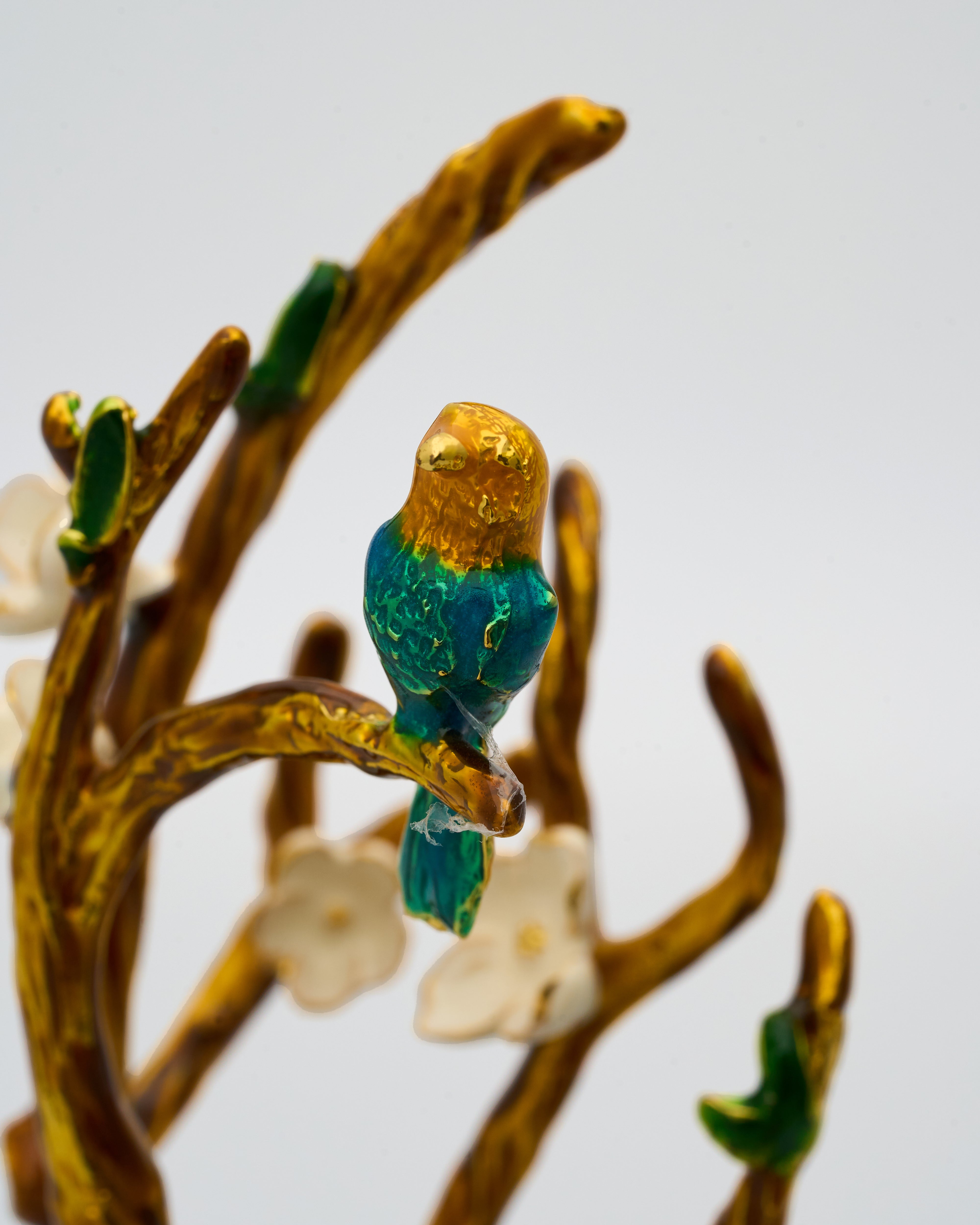 Decorative brooch with a bird on a branch against a light background