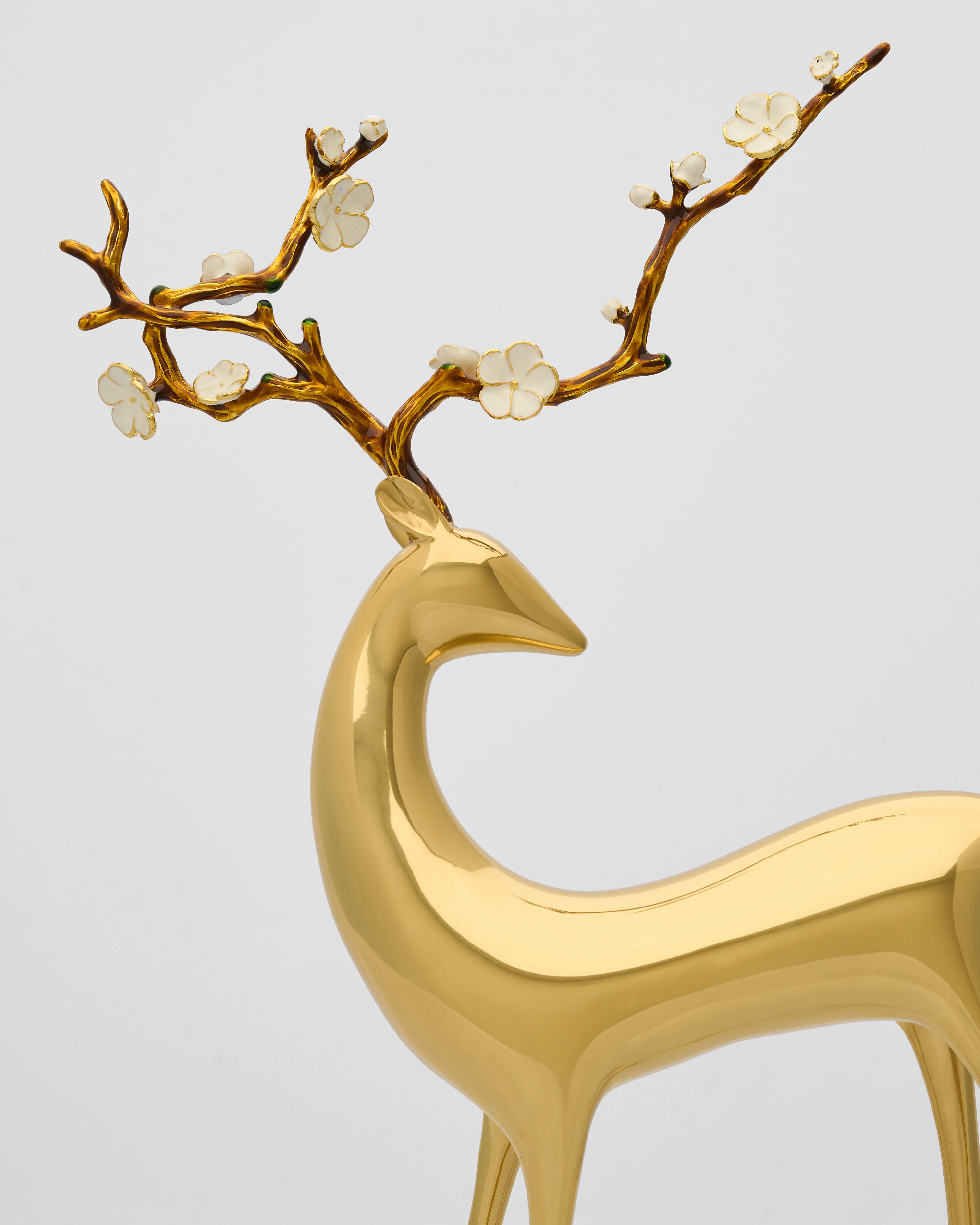 Gold deer figurine with decorative antlers on a light gray background