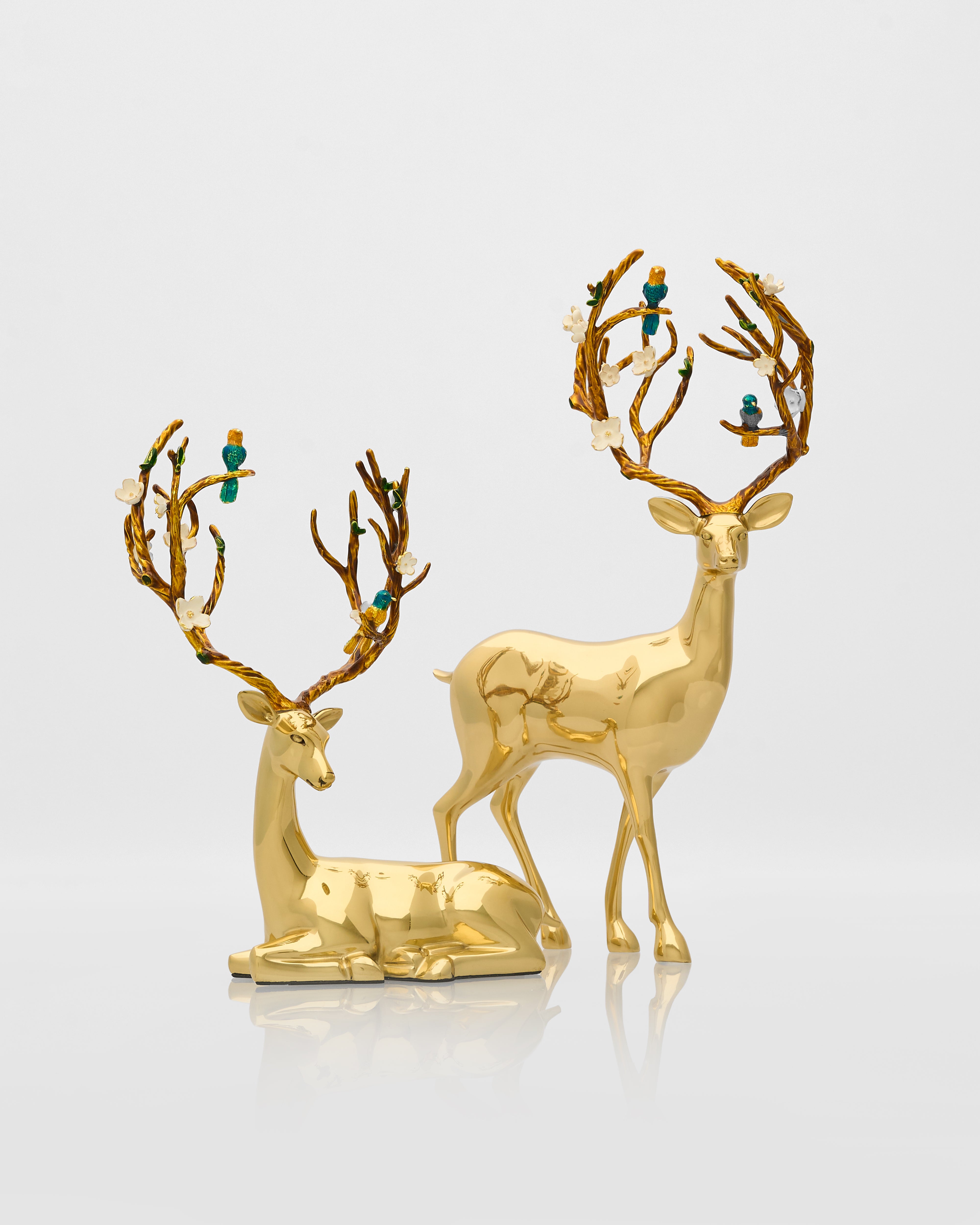 Two gold deer figurines with decorative antlers on a light gray background