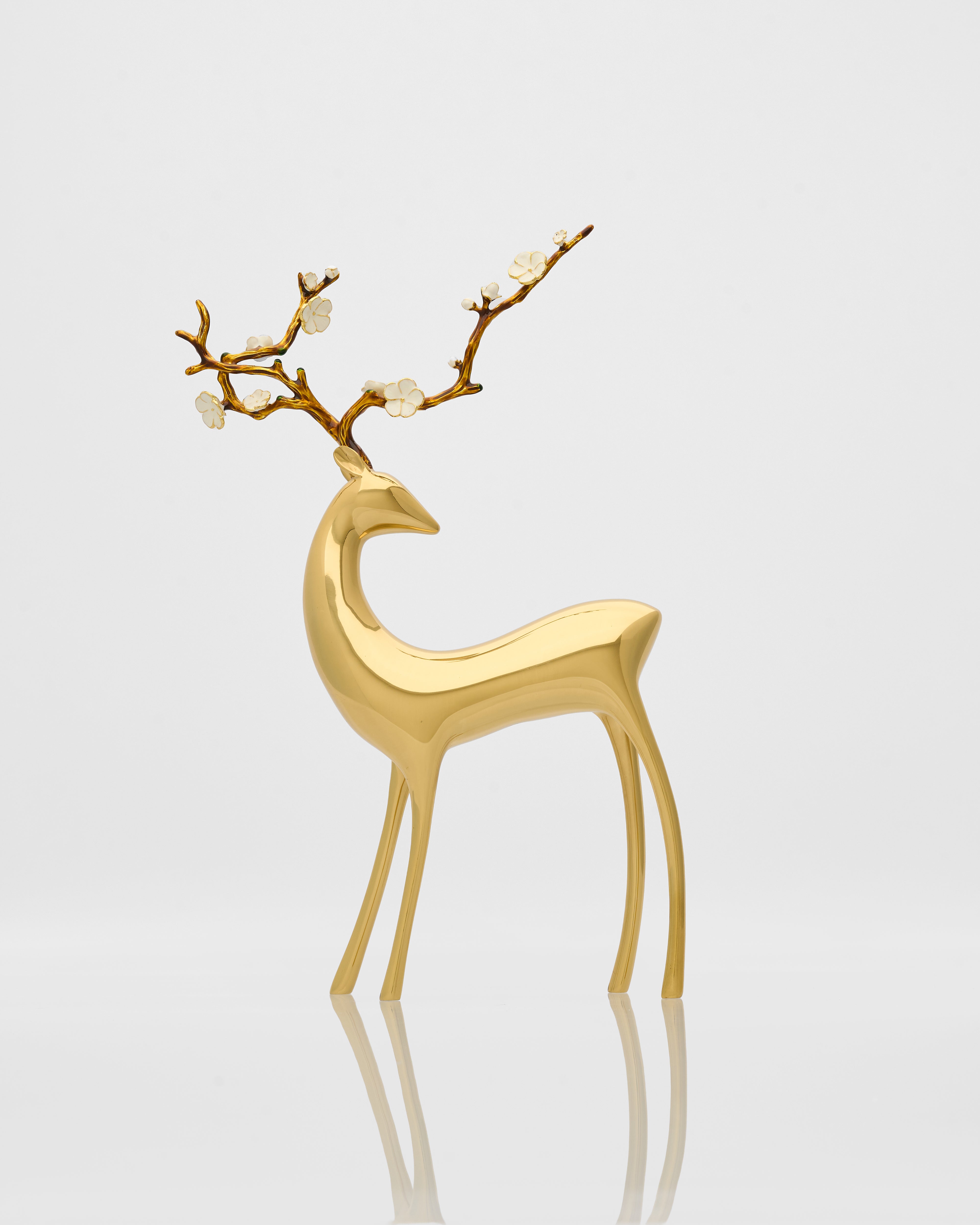 Gold deer figurine with branch antlers on a light gray background