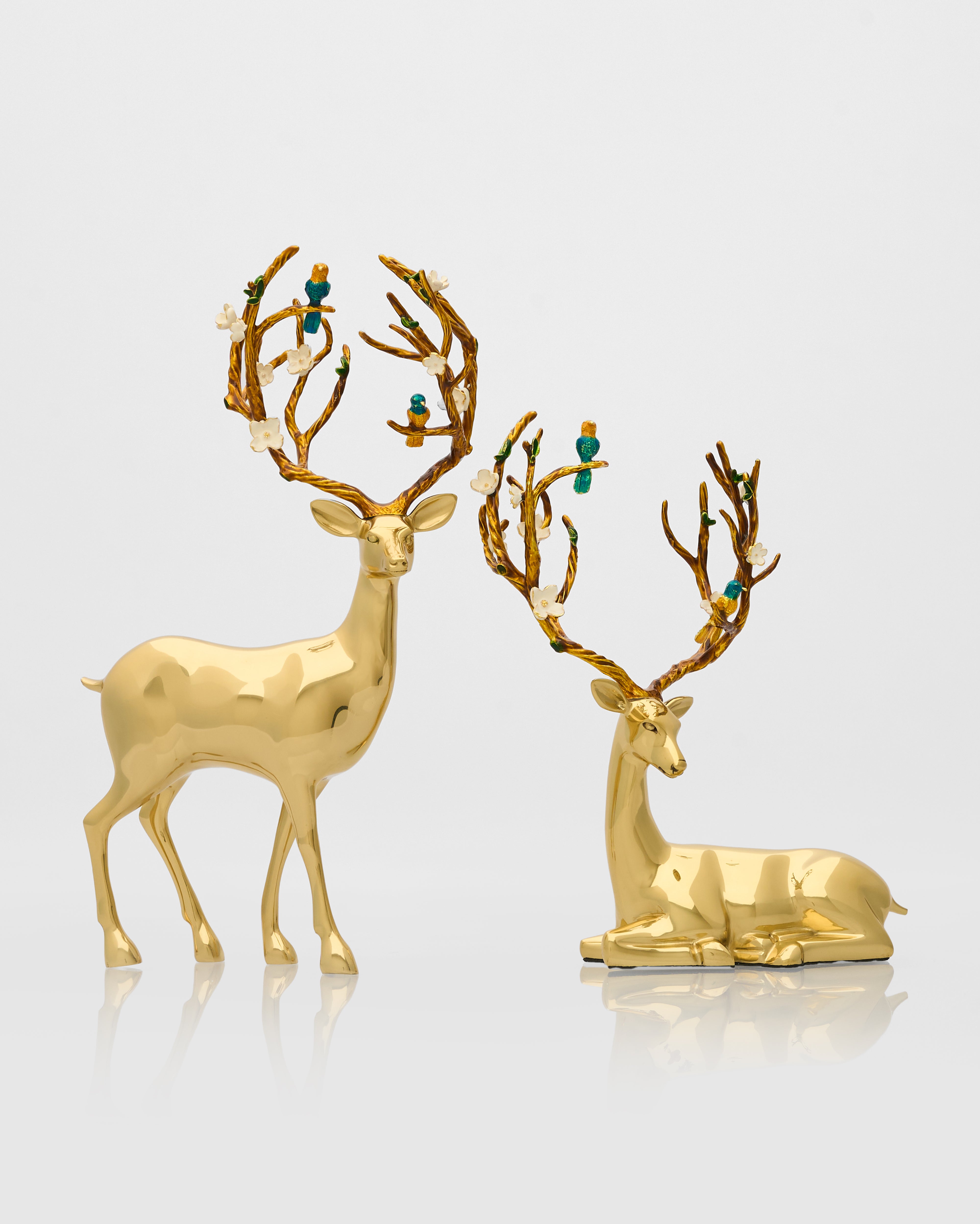 Two gold deer figurines with decorative antlers on a light gray background