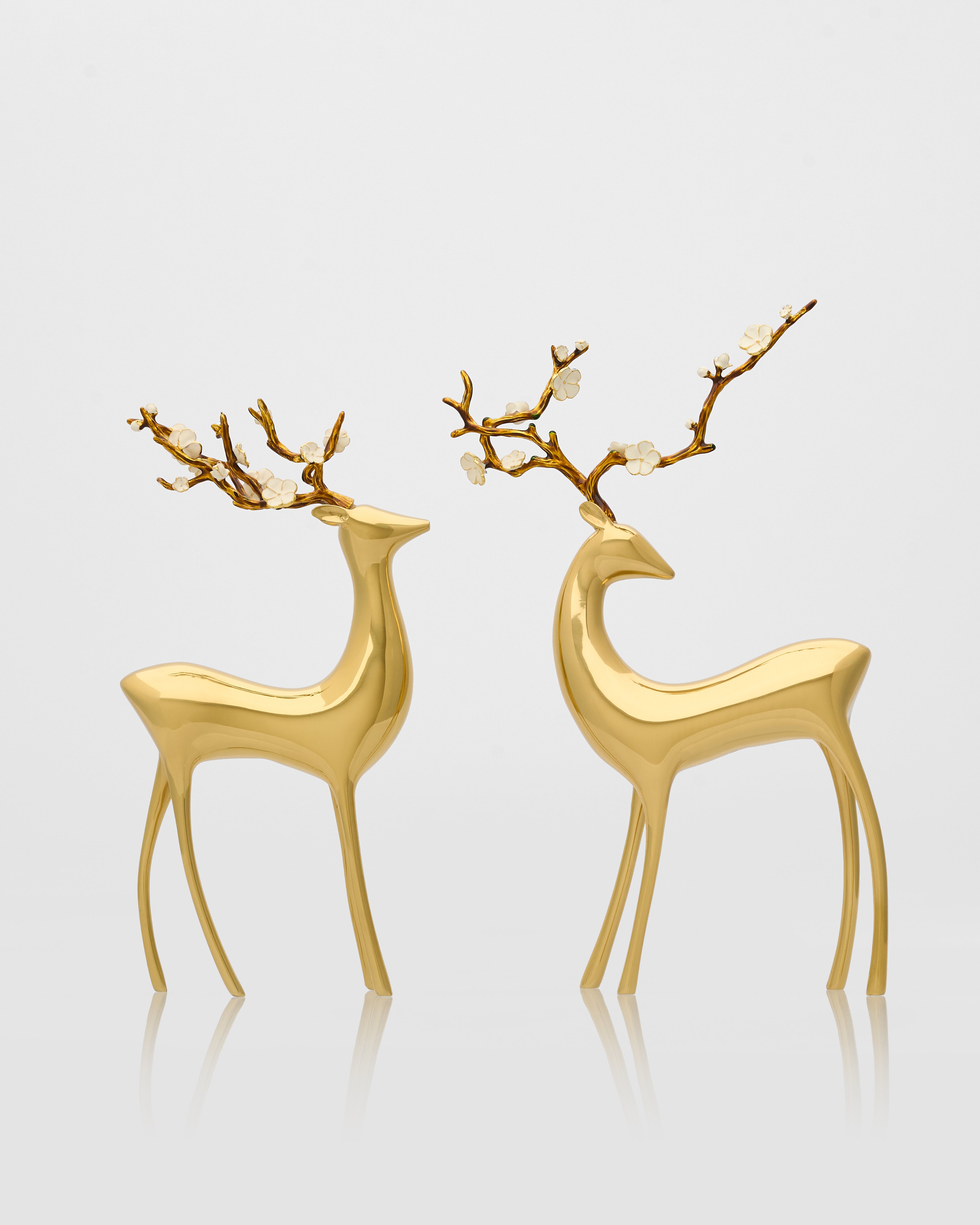 Two gold deer figurines with branch antlers on a light gray background