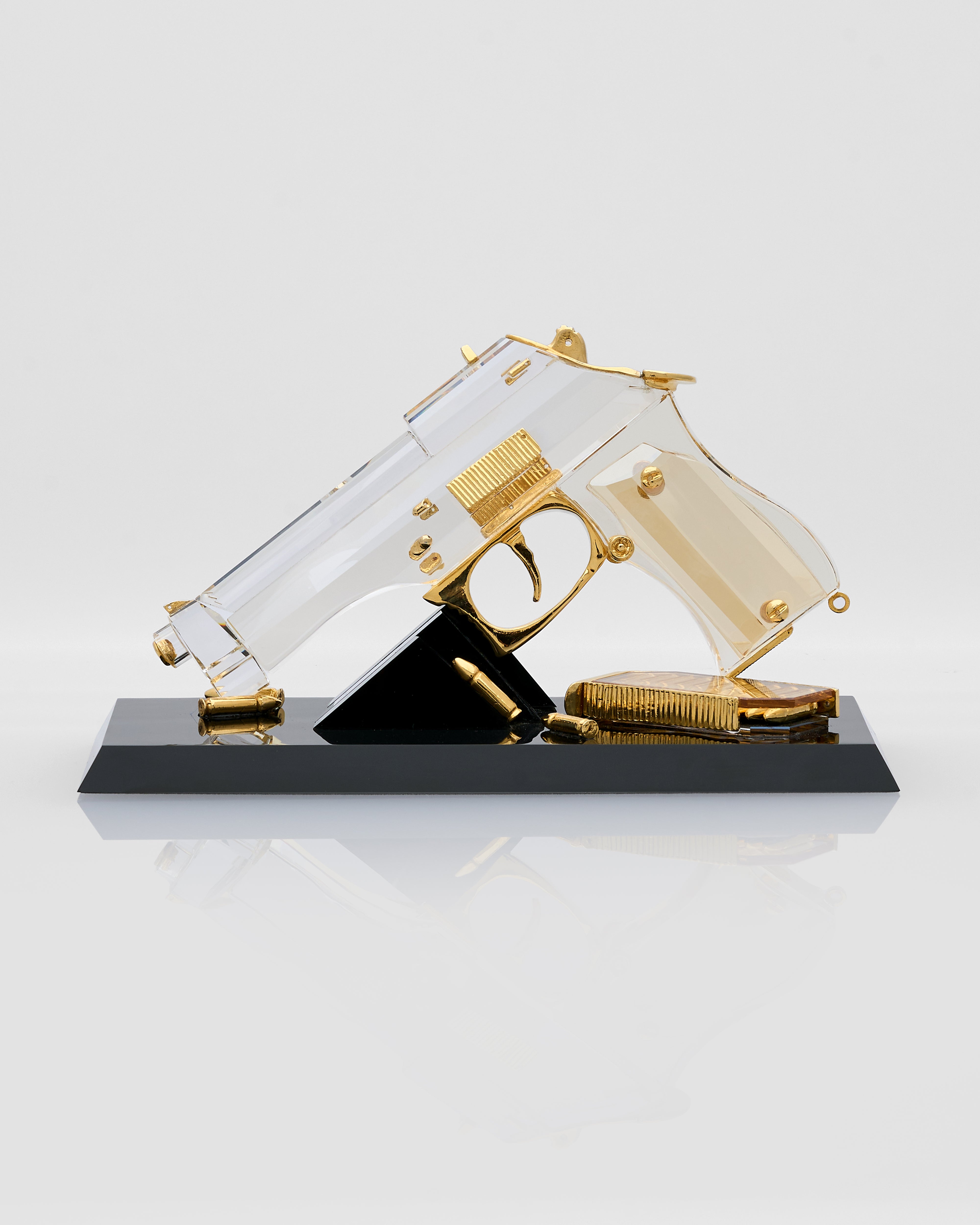 Decorative gun shaped accessory with gold accents on a black base against a white background