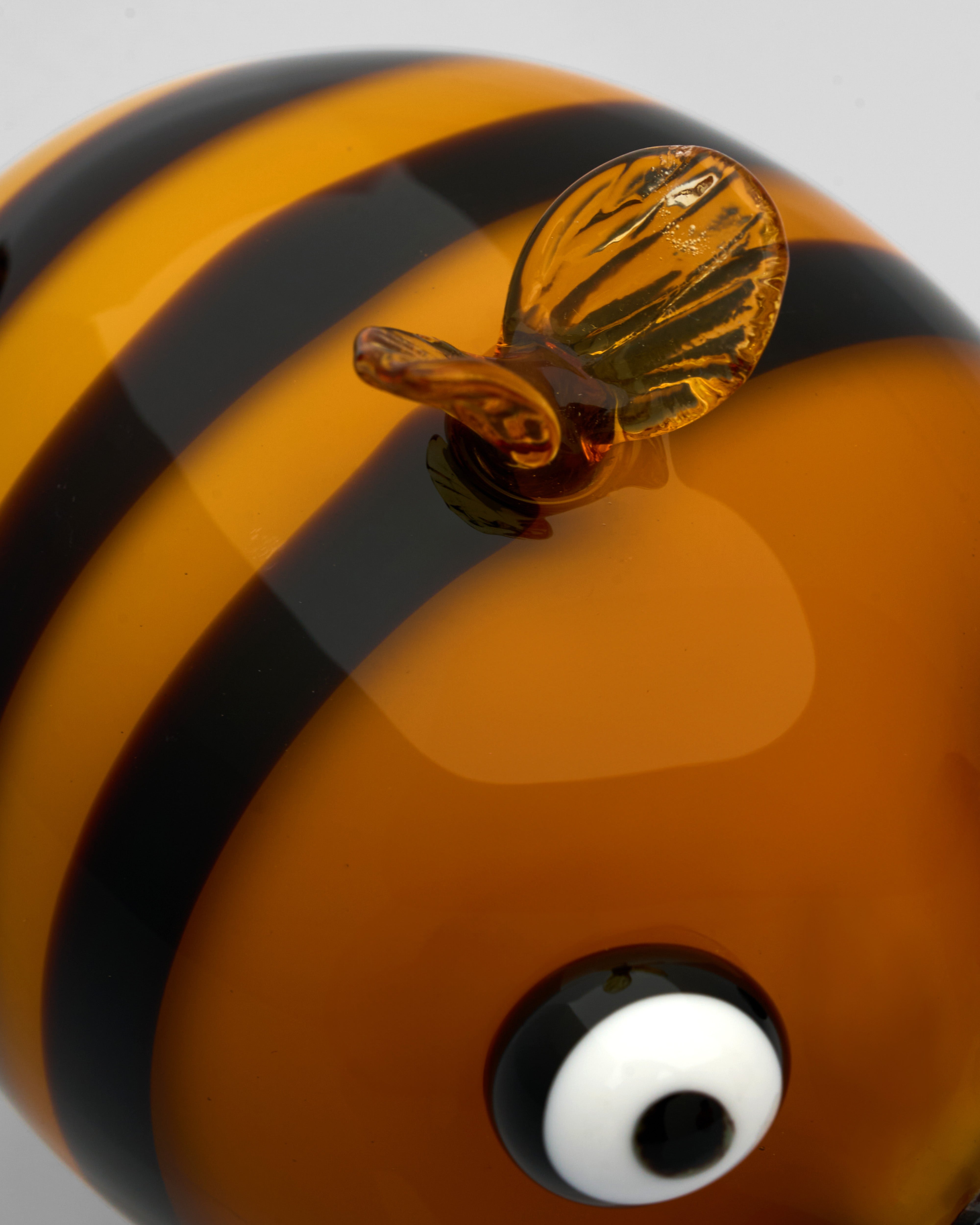 Close-up of a glass bee with black and orange stripes on a gray background
