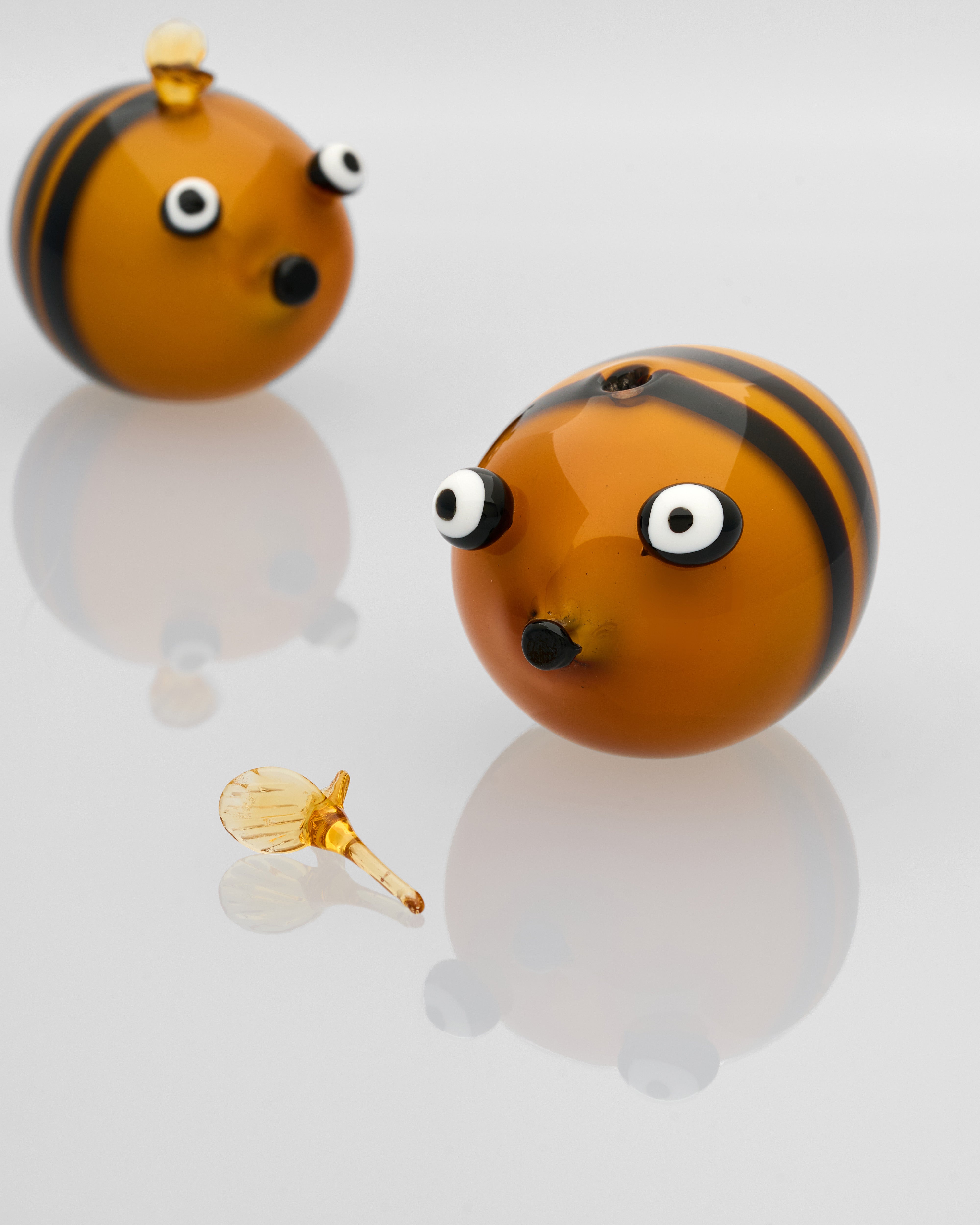 Two bee-shaped earrings with a small bee figurine on a white background