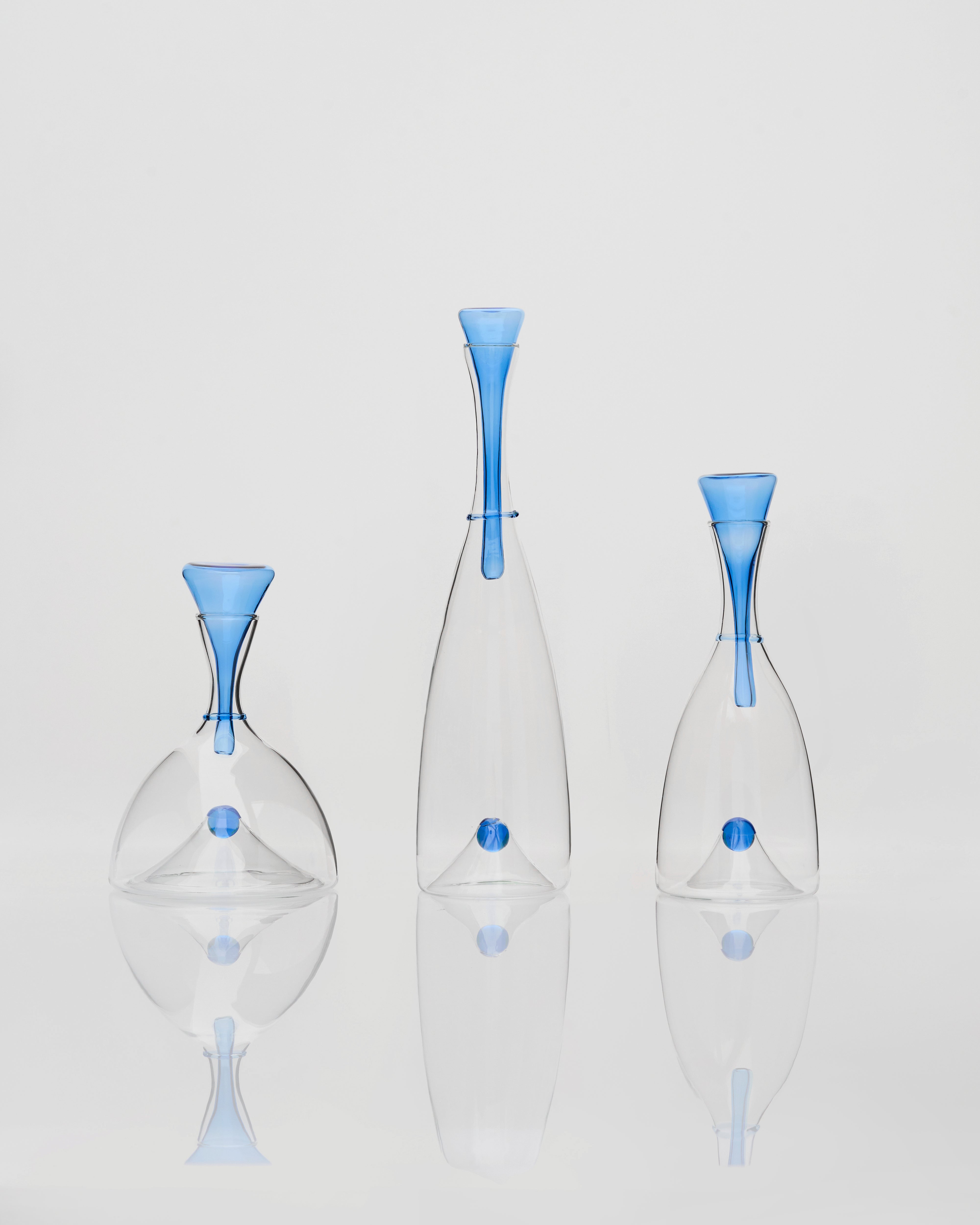 Three glass vases with blue accents on a light gray background