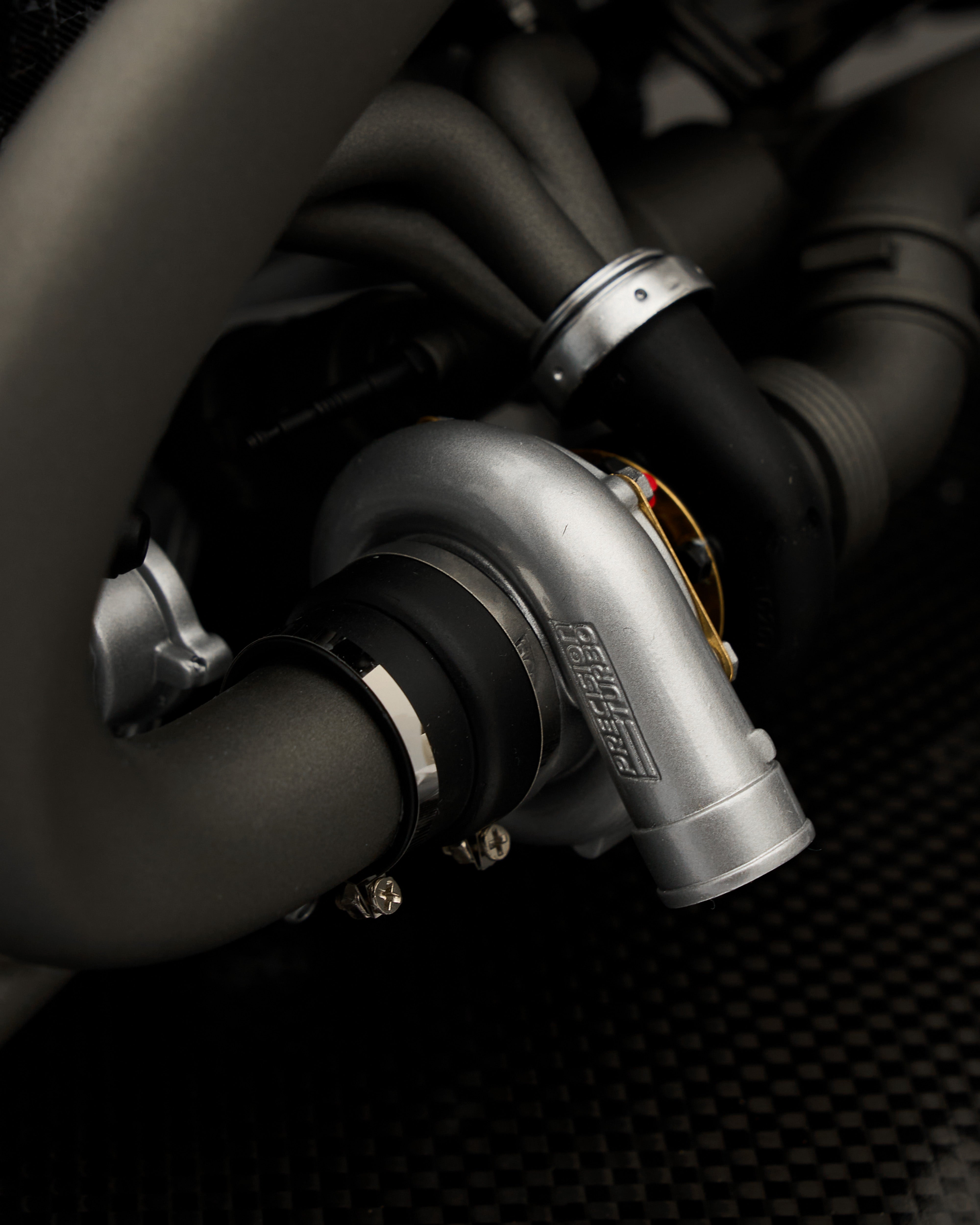 Close-up of a car engine with a turbocharger and pipes on a dark background