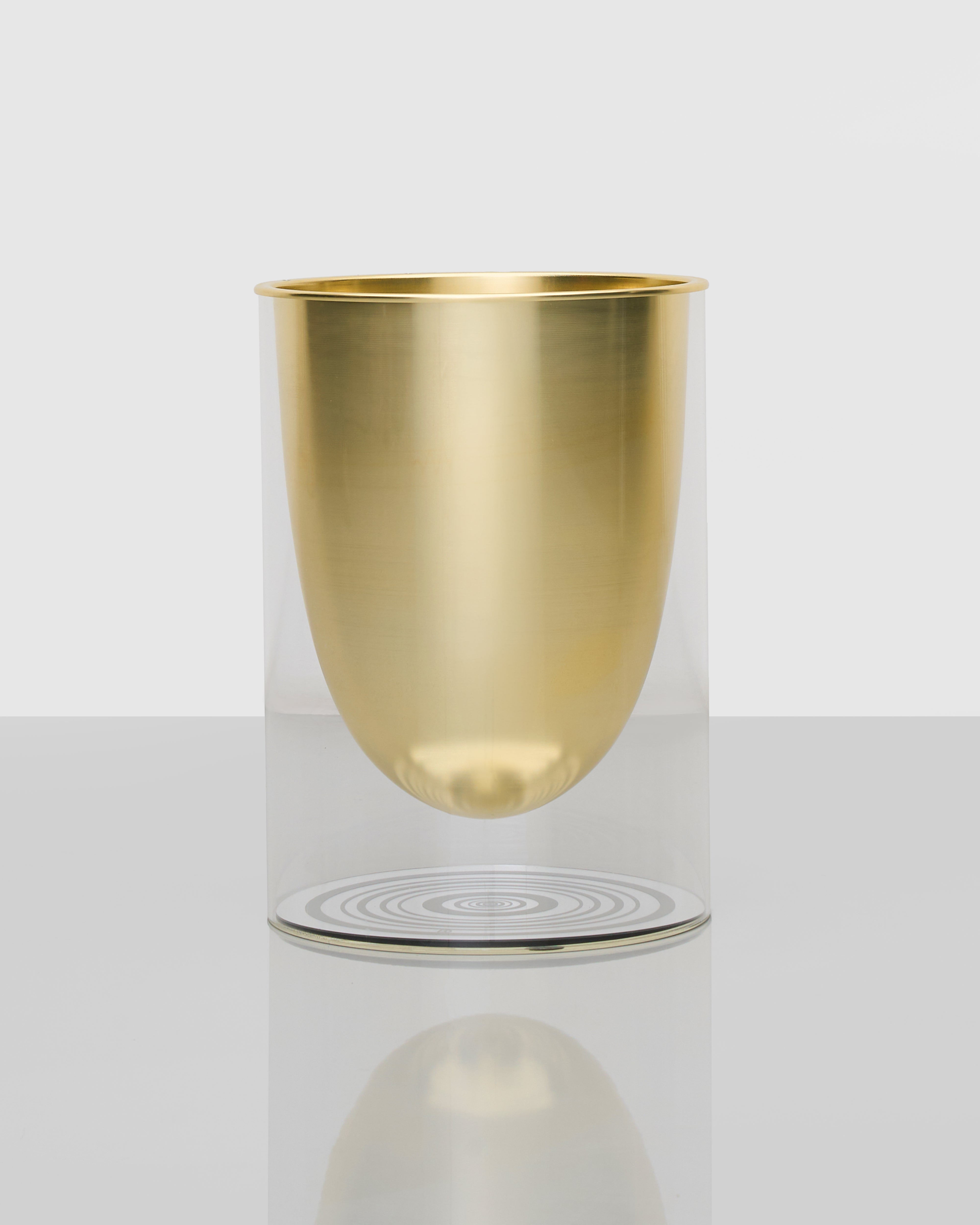 Gold metallic cup levitating above a circular base on a white background