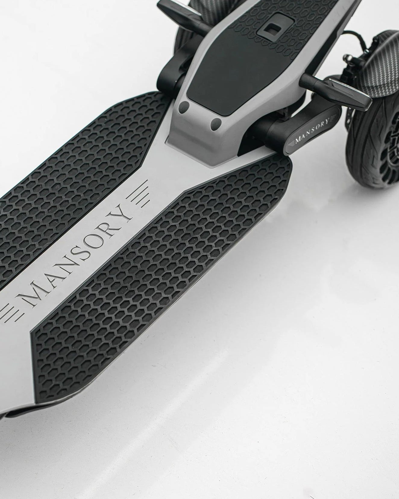 Close-up of a scooter with 'Mansory' branding on a white background