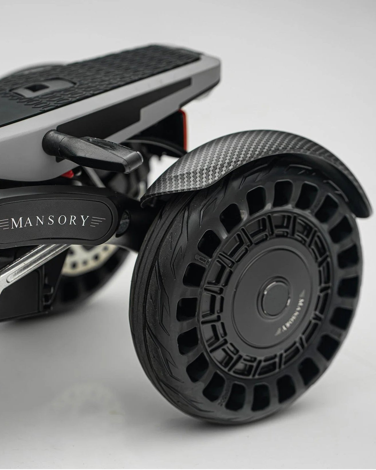 Close-up of a MANSORY branded scooter on a light gray background