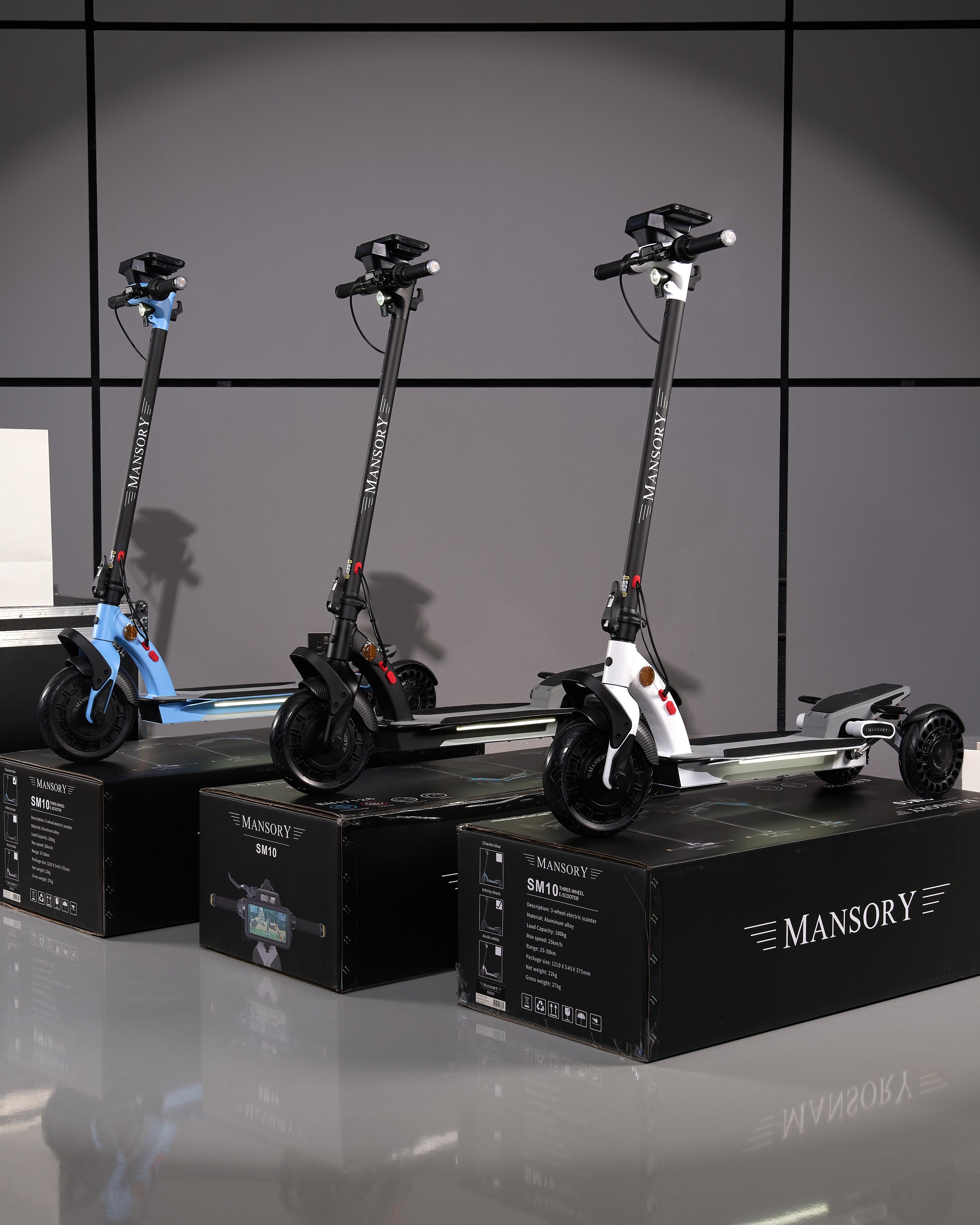 Three electric scooters on stands with 'Mansory' branding against a dark background.