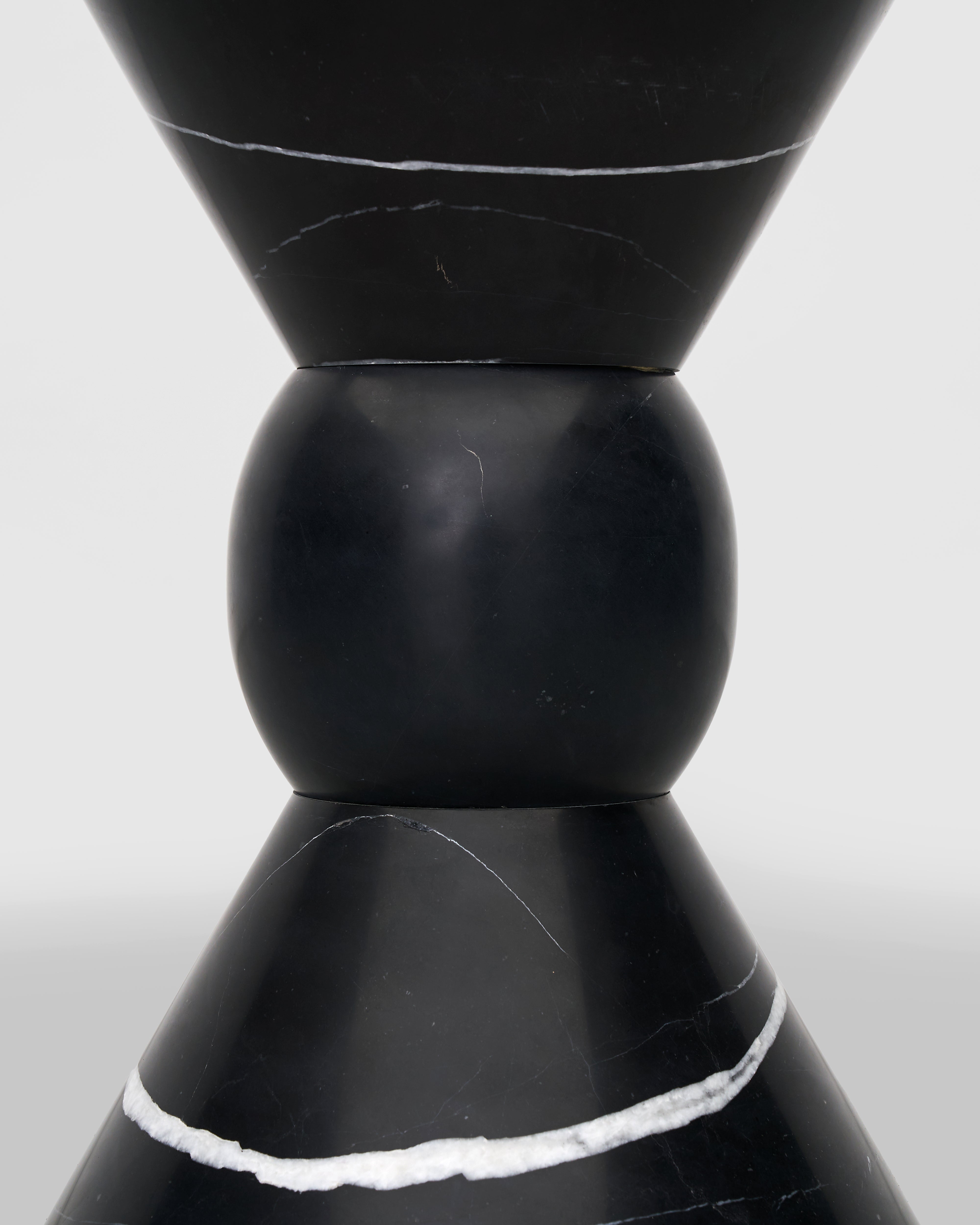 Close-up of a black ceramic vase with white accents on a light gray background