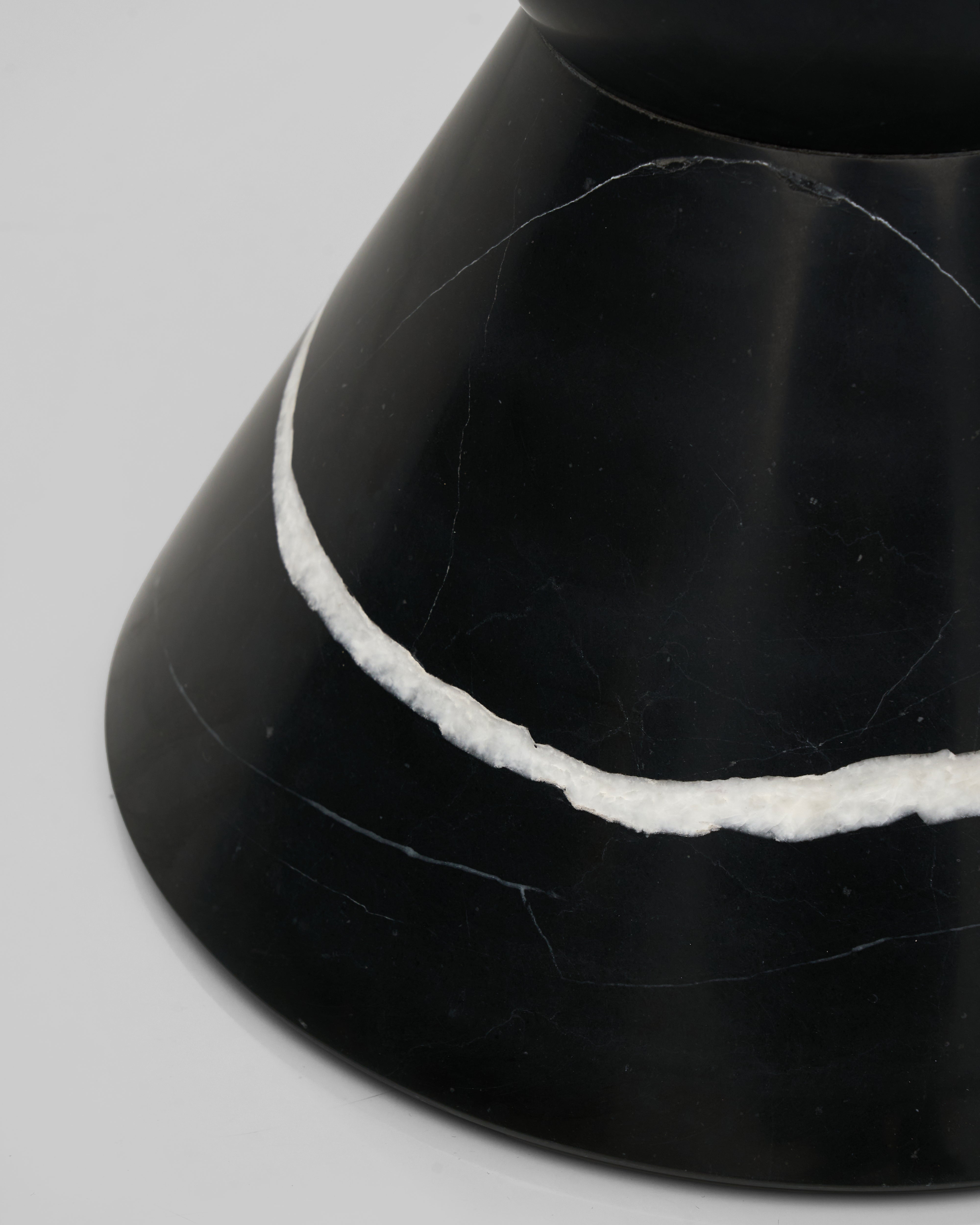 Close-up of a black marble object with a white line on a gray background