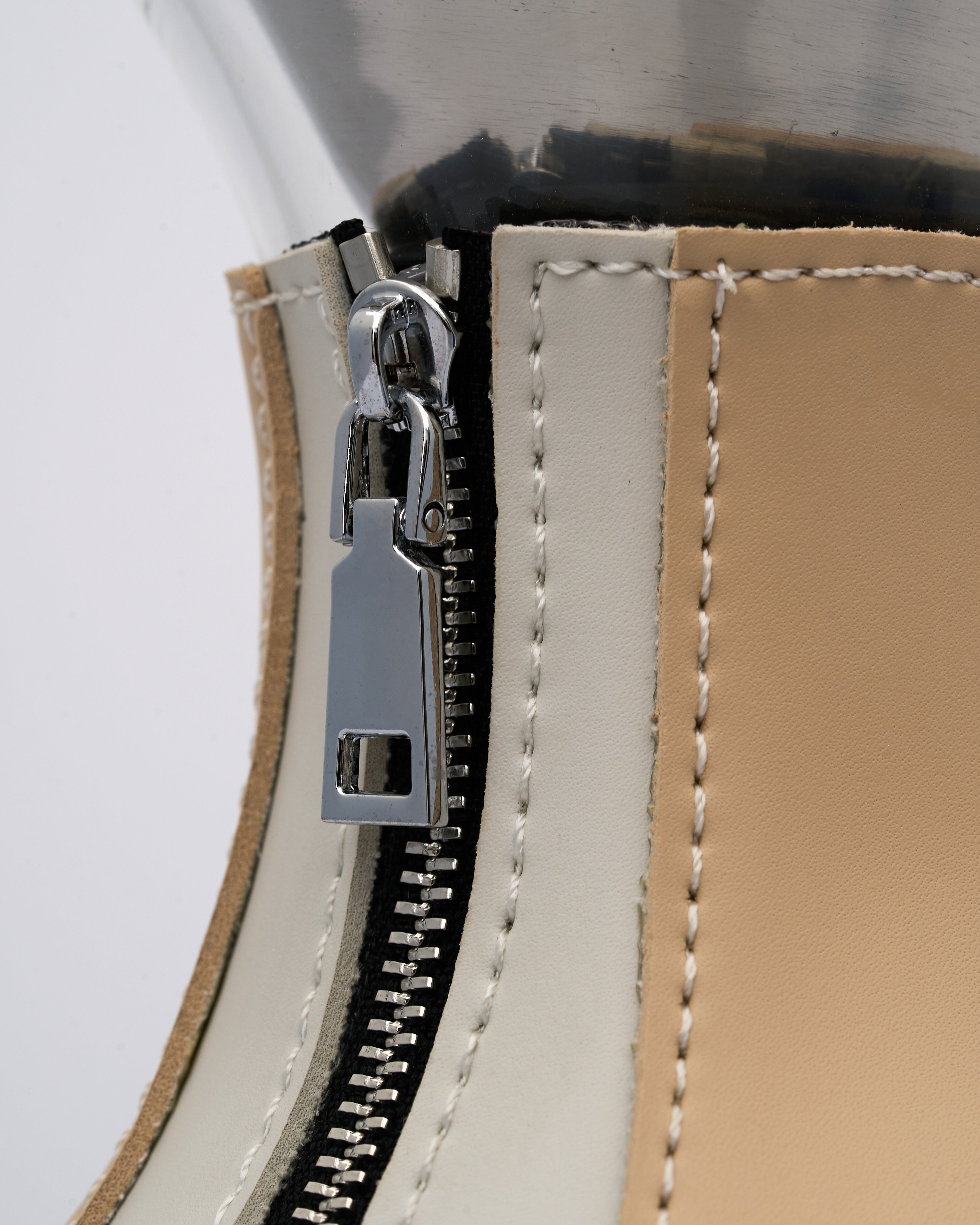 Close-up of a zipper on a leather product with a white background