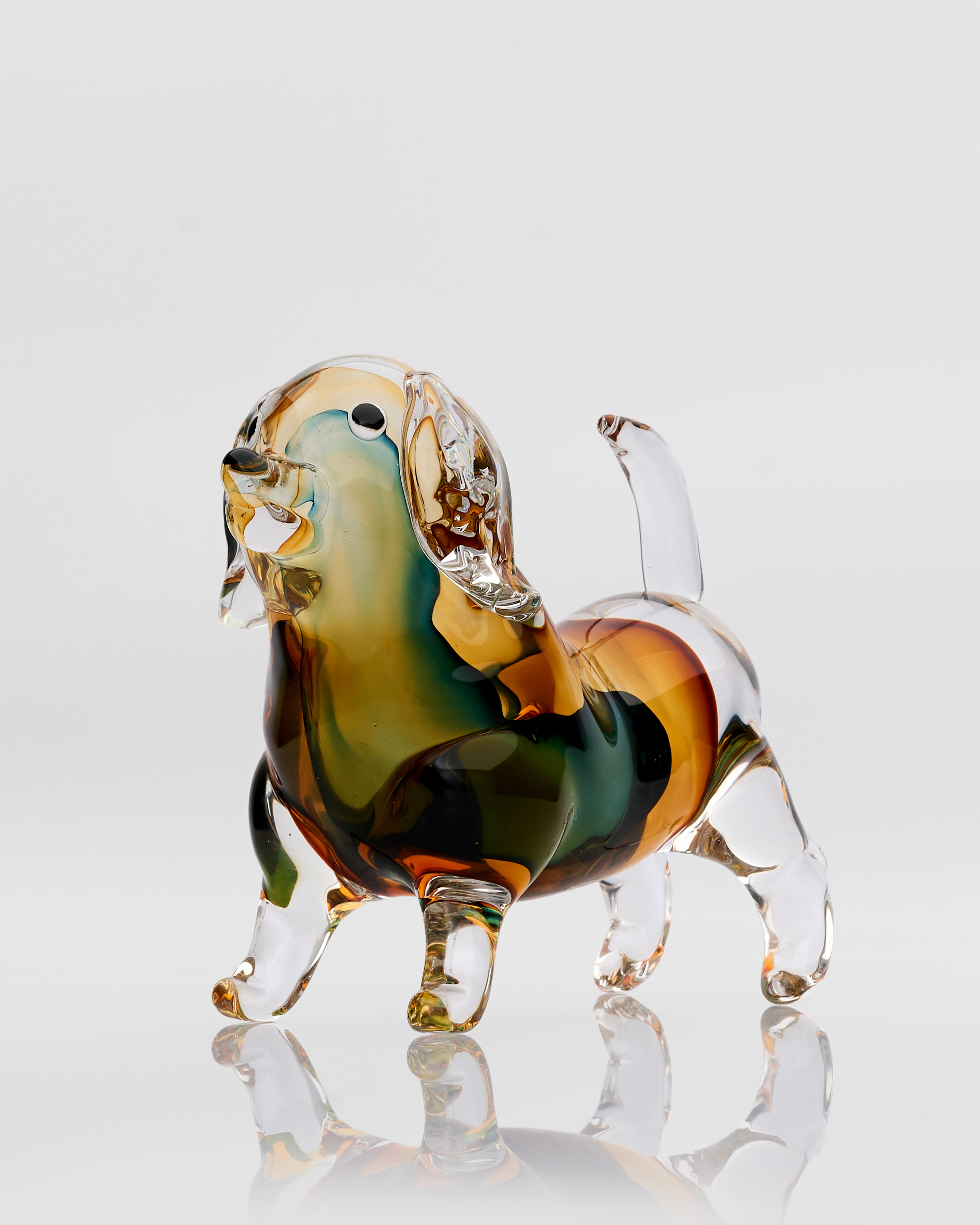 Colorful glass dog figurine on a reflective surface with a light gray background