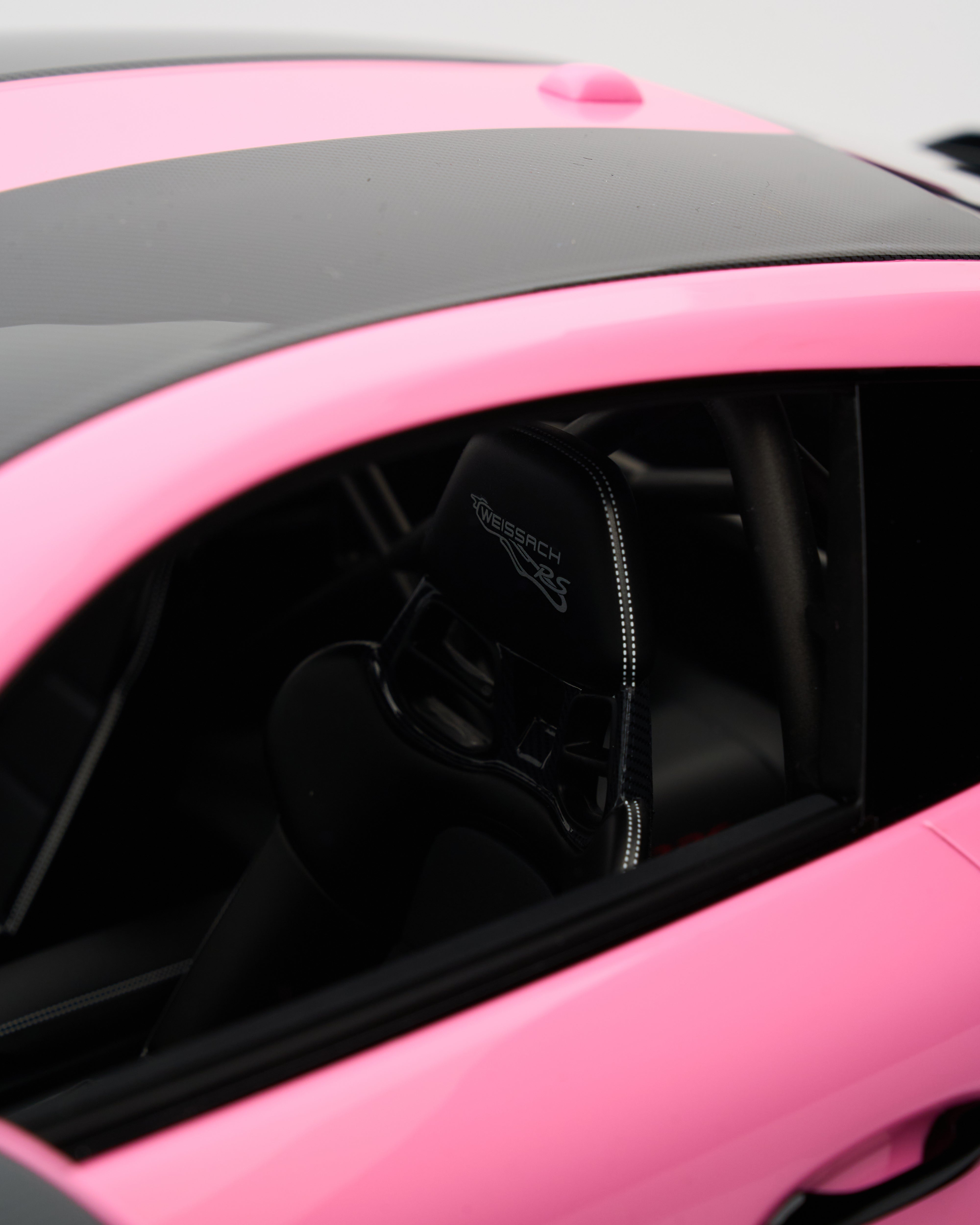 Close-up of a pink car with a black premium seats inside the window side mirror