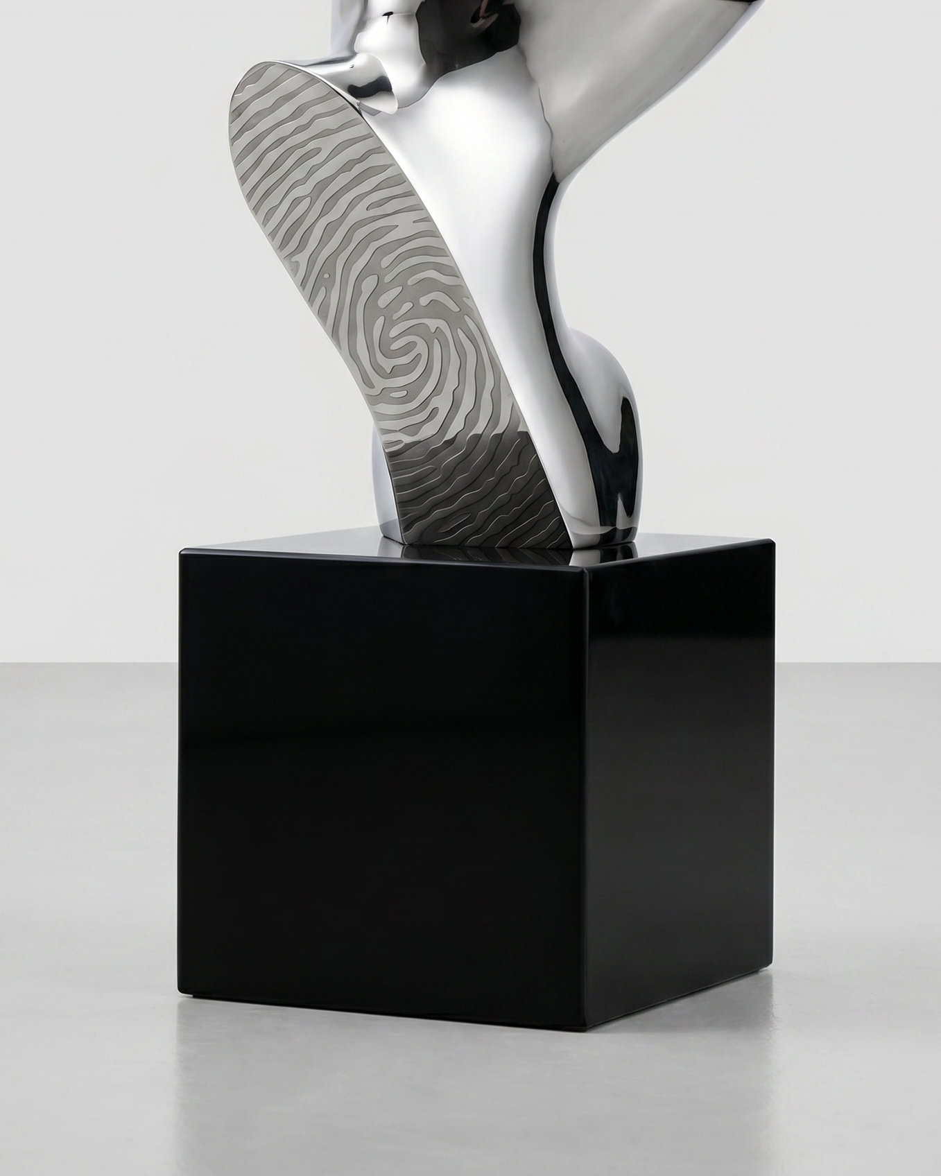 Metallic sculpture on a black base against a light gray background