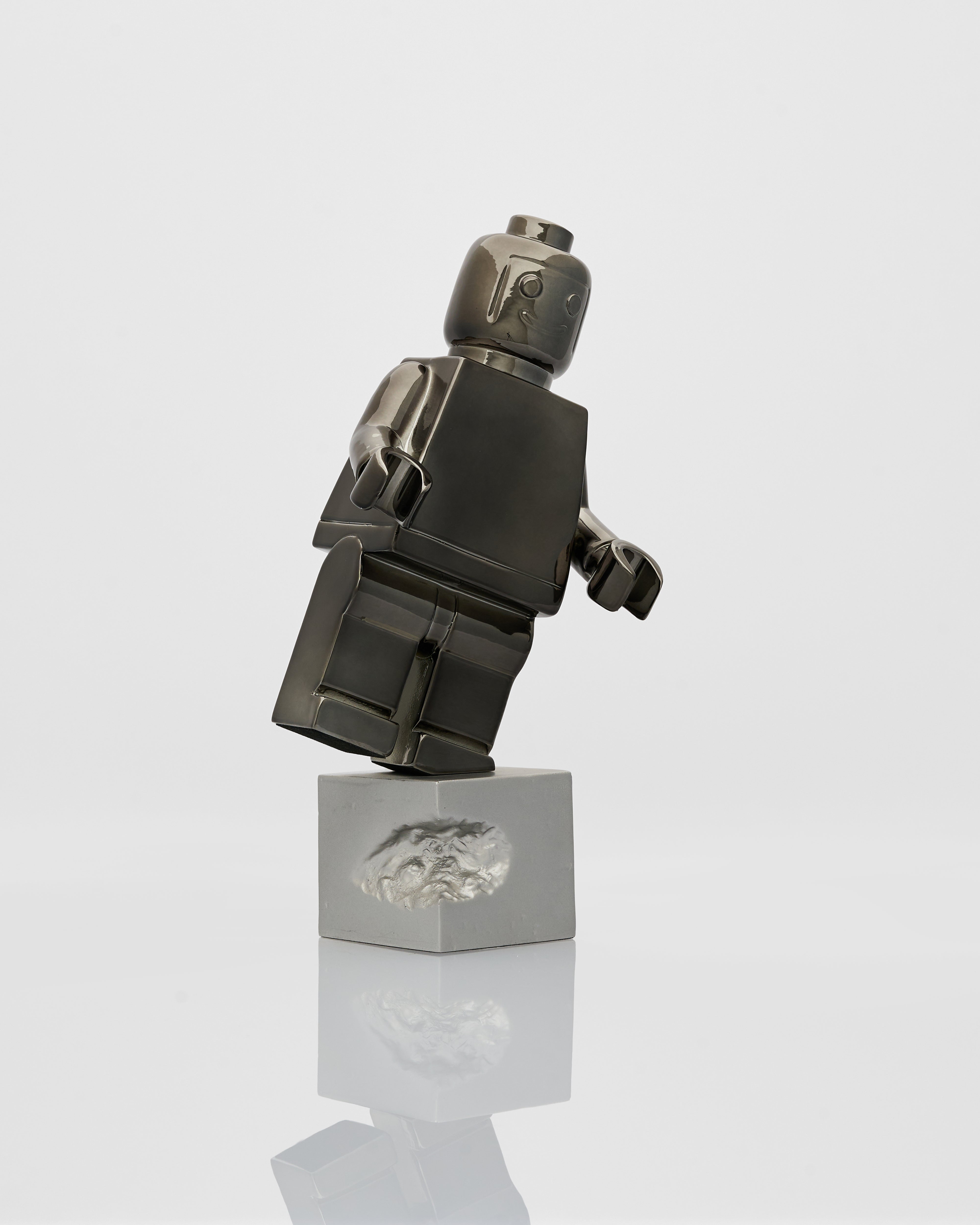 Black and silver robo figure on a reflective surface with a white background