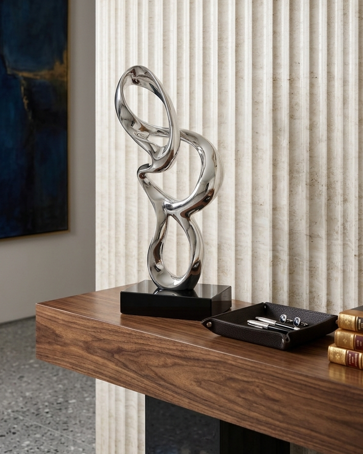 Abstract silver sculpture on a wooden console table with a neutral wall background