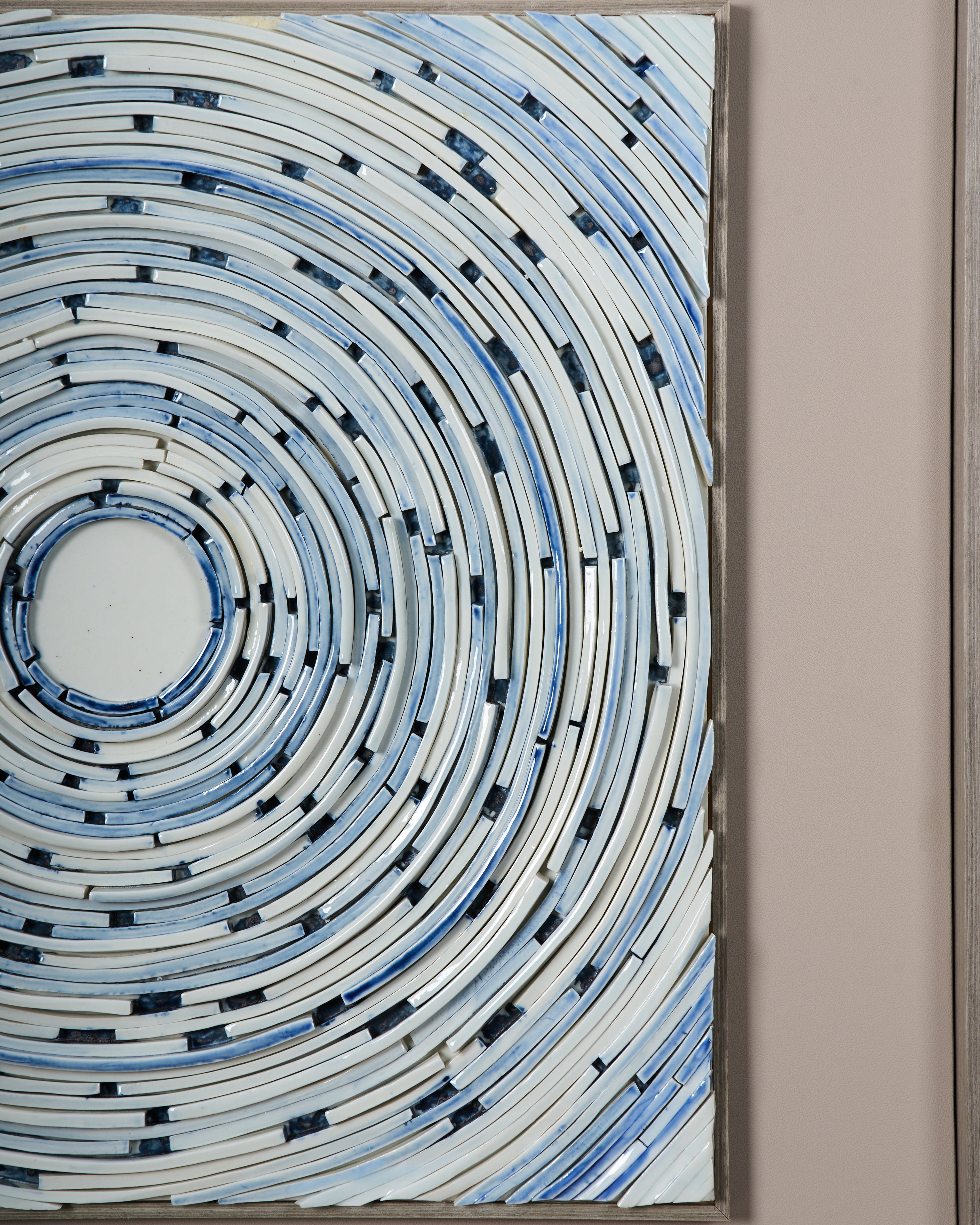 Abstract circular artwork with concentric patterns on a beige wall