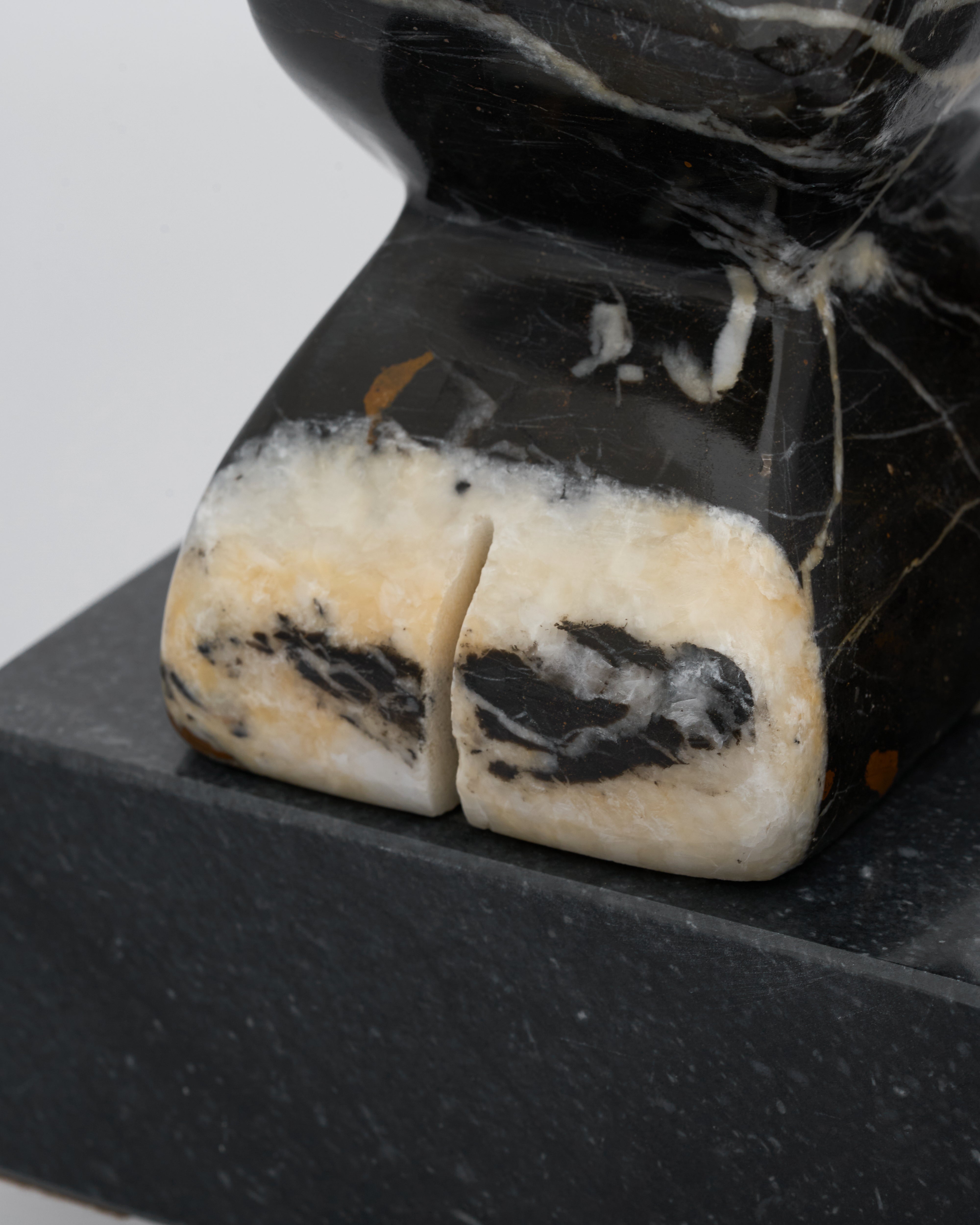 Two stone-like objects on a black stand with a white background