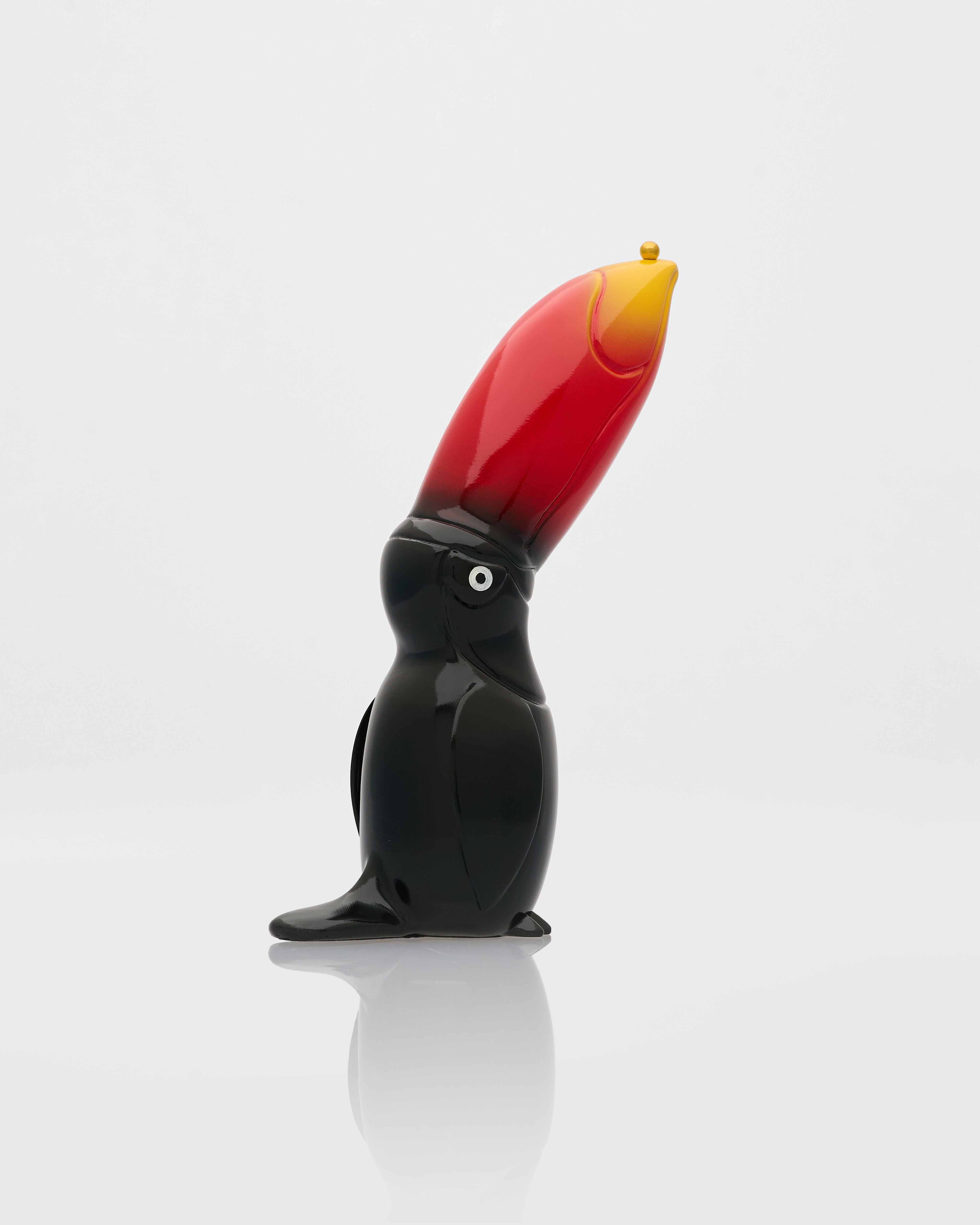 Glass sculpture of a toucan with a red beak on a white background