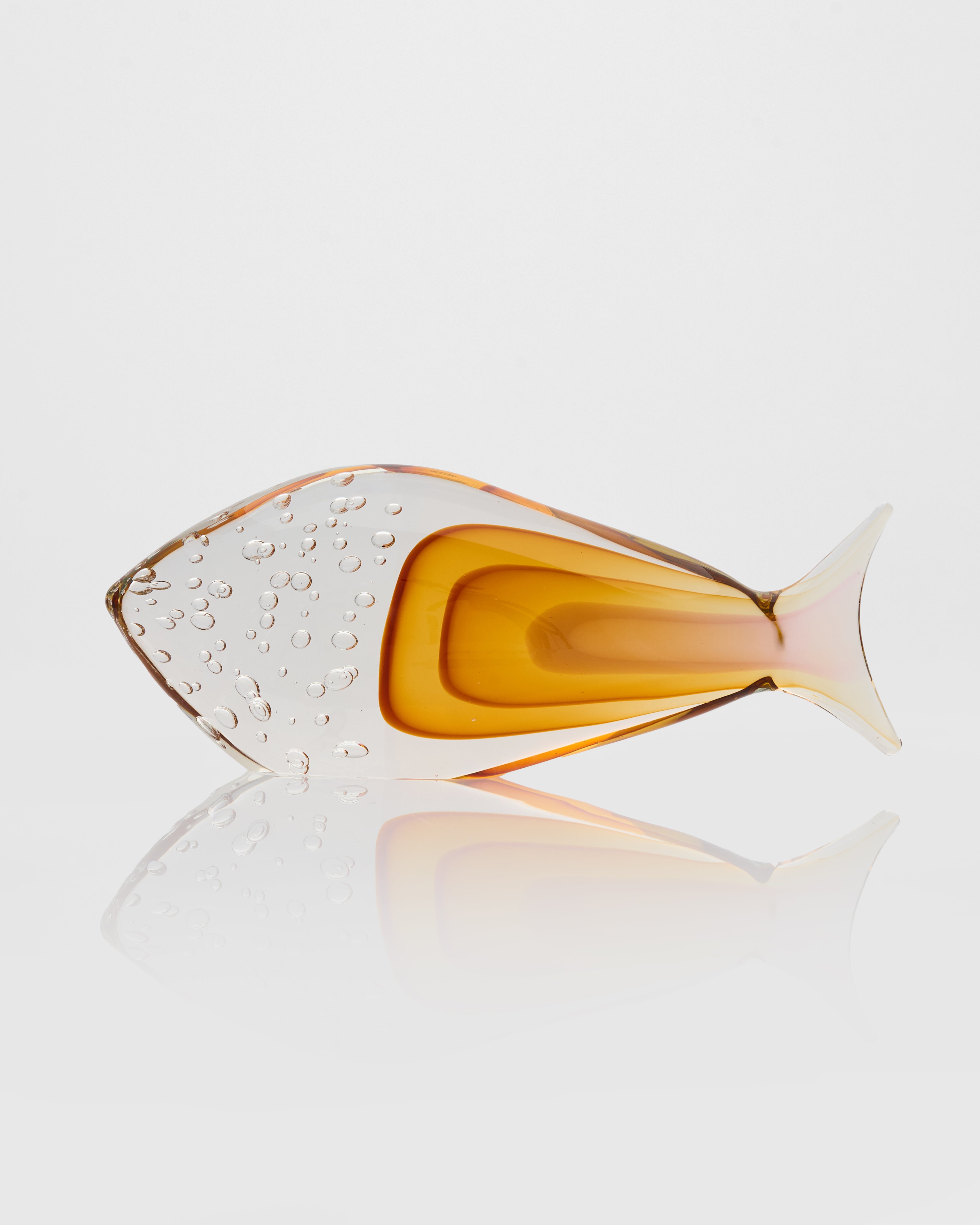Glass fish-shaped object with gradient color on a reflective surface
