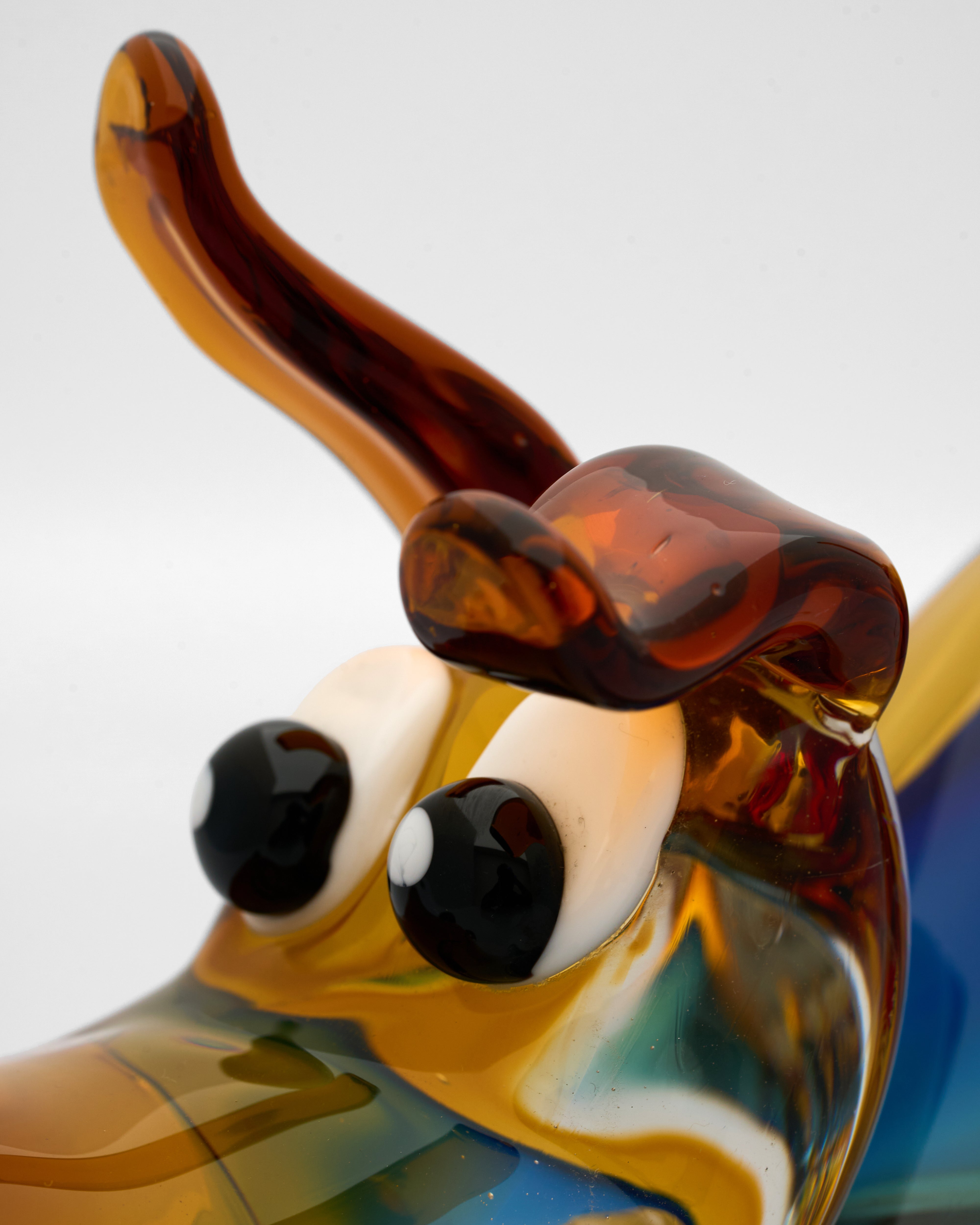 Glass sculpture of a dog with a brown bow tie on a white background