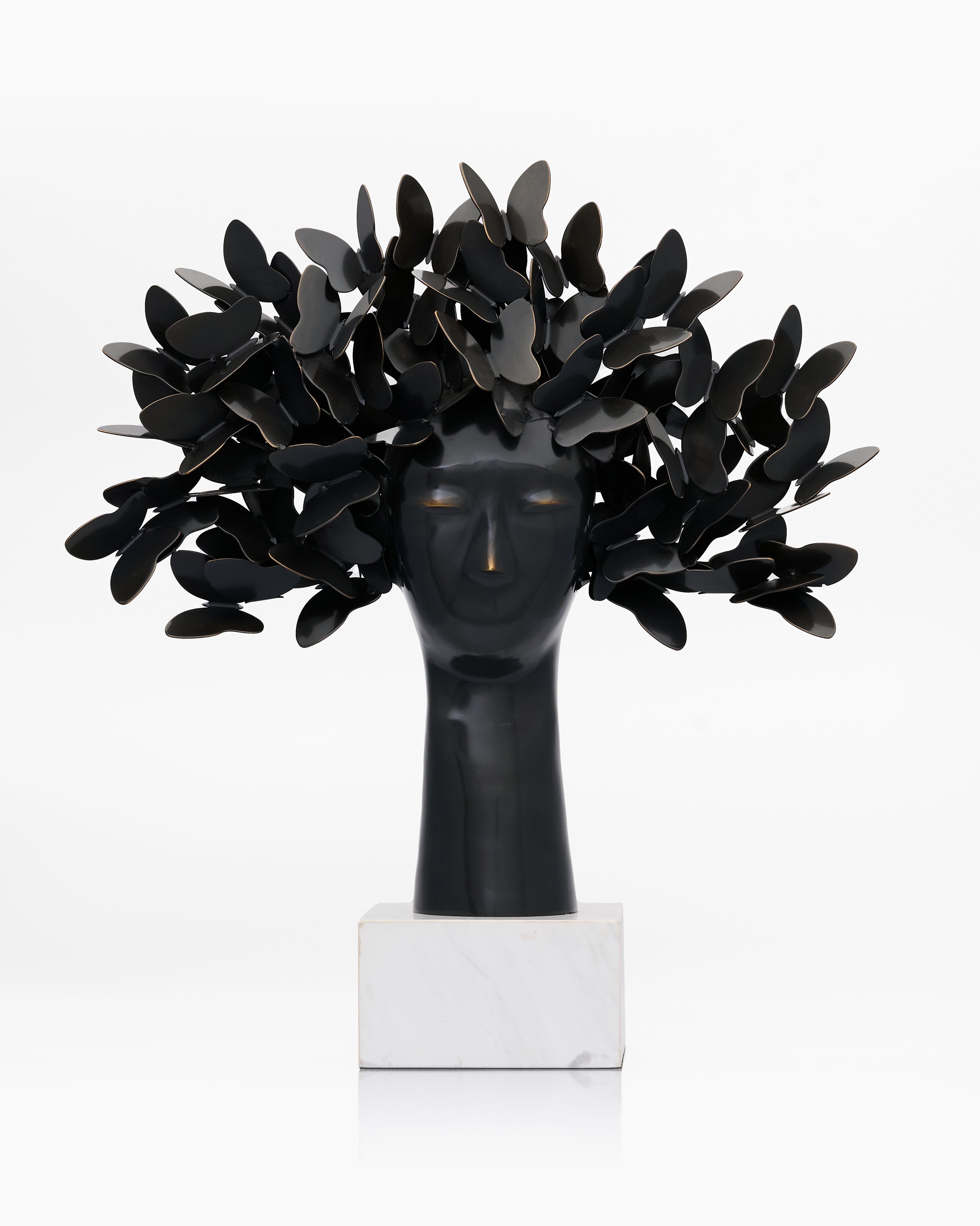 Black sculpture of a head with leaf-like structures on a white background