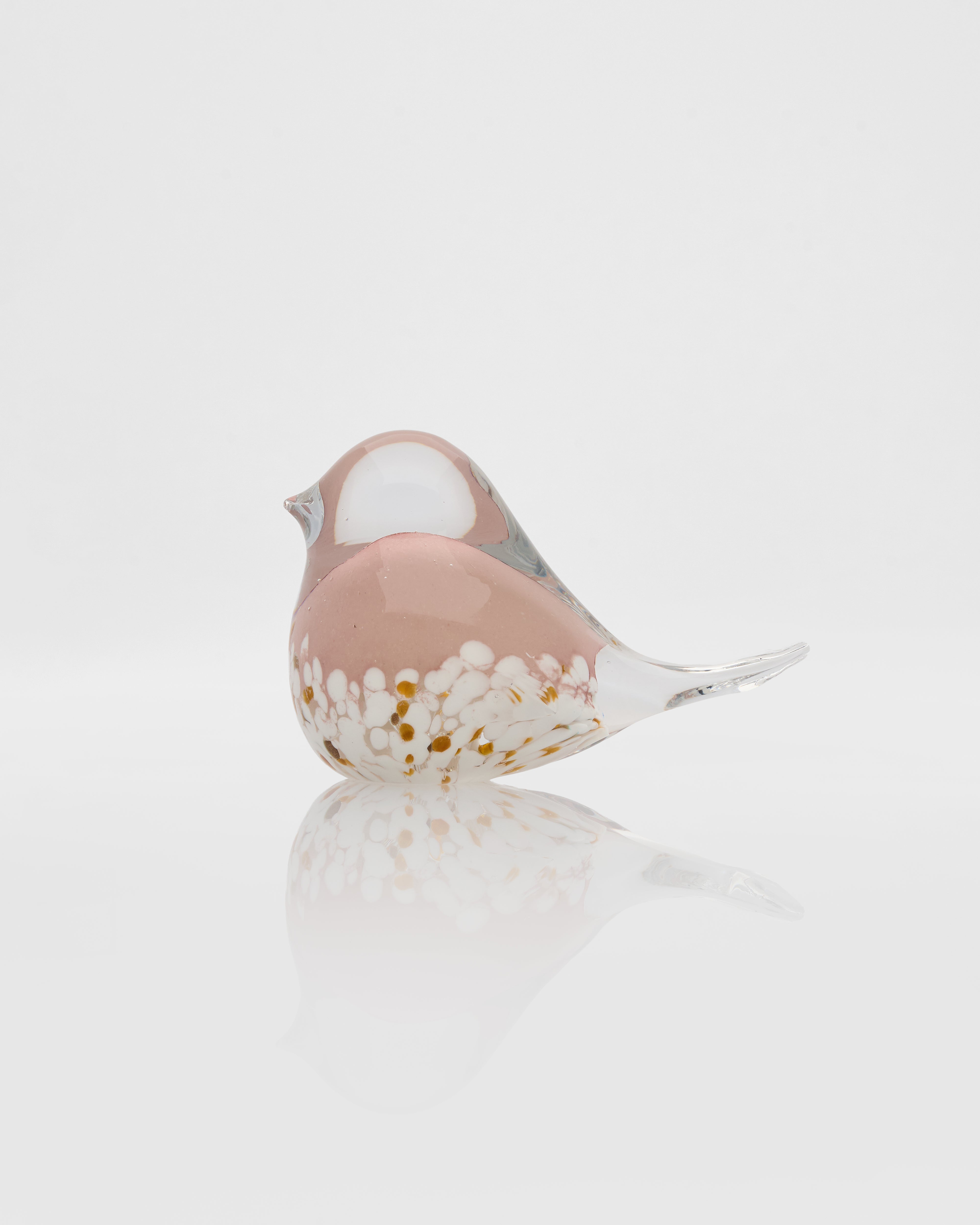 Glass bird figurine with a pink and white pattern on a reflective surface