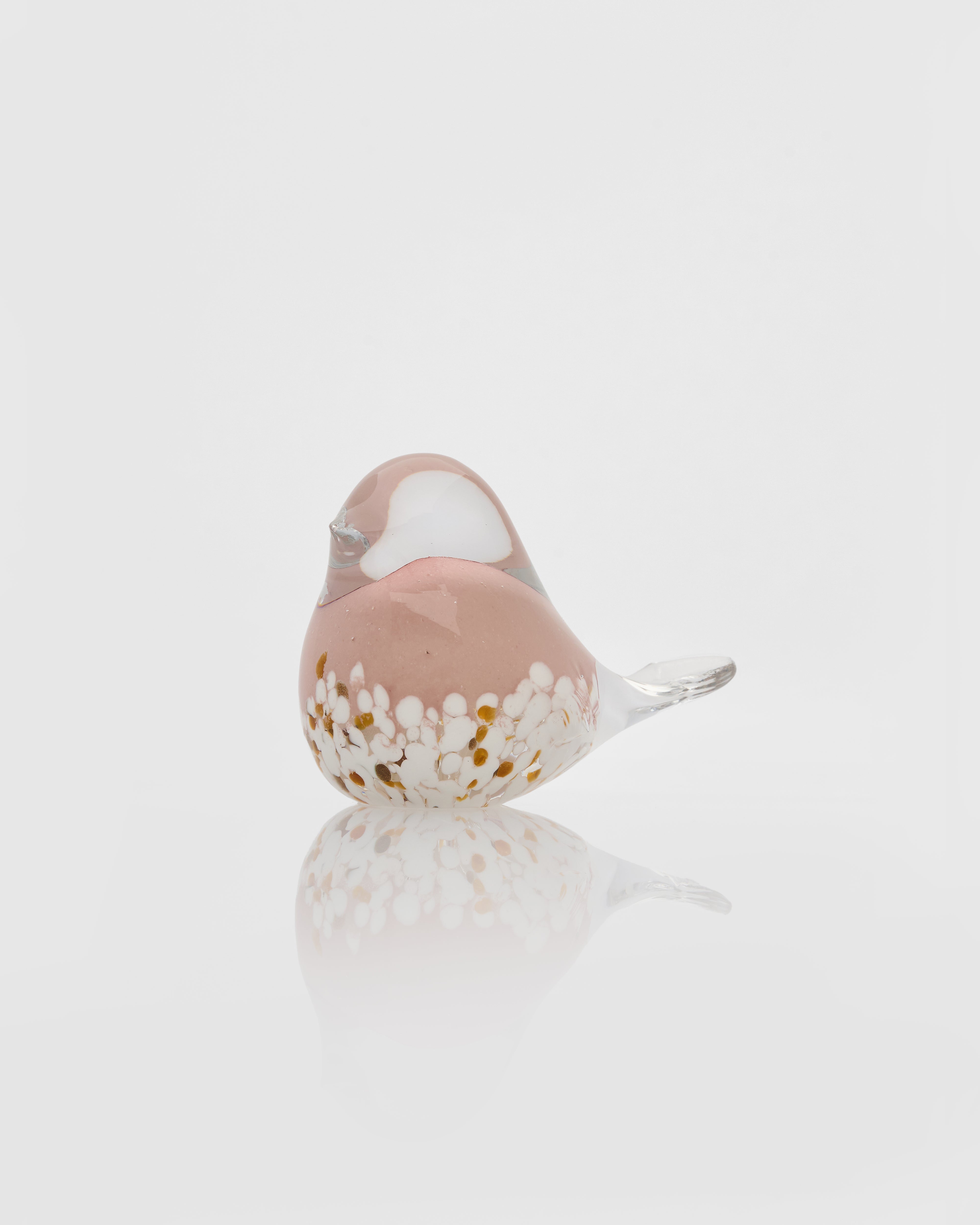 Glass bird figurine with a pink breast on a light gray background