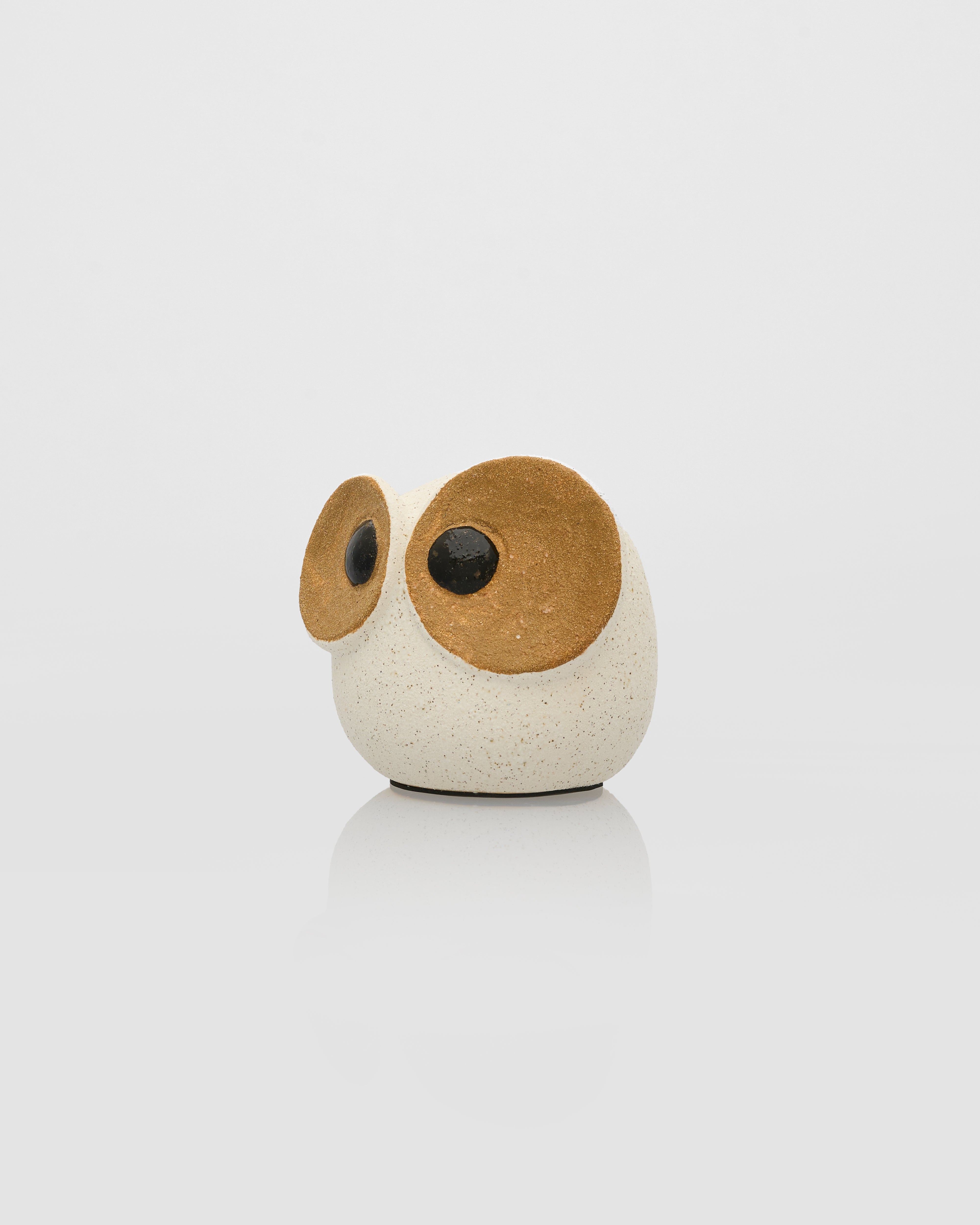 Small round ceramic owl figurine with wooden wings on a white background