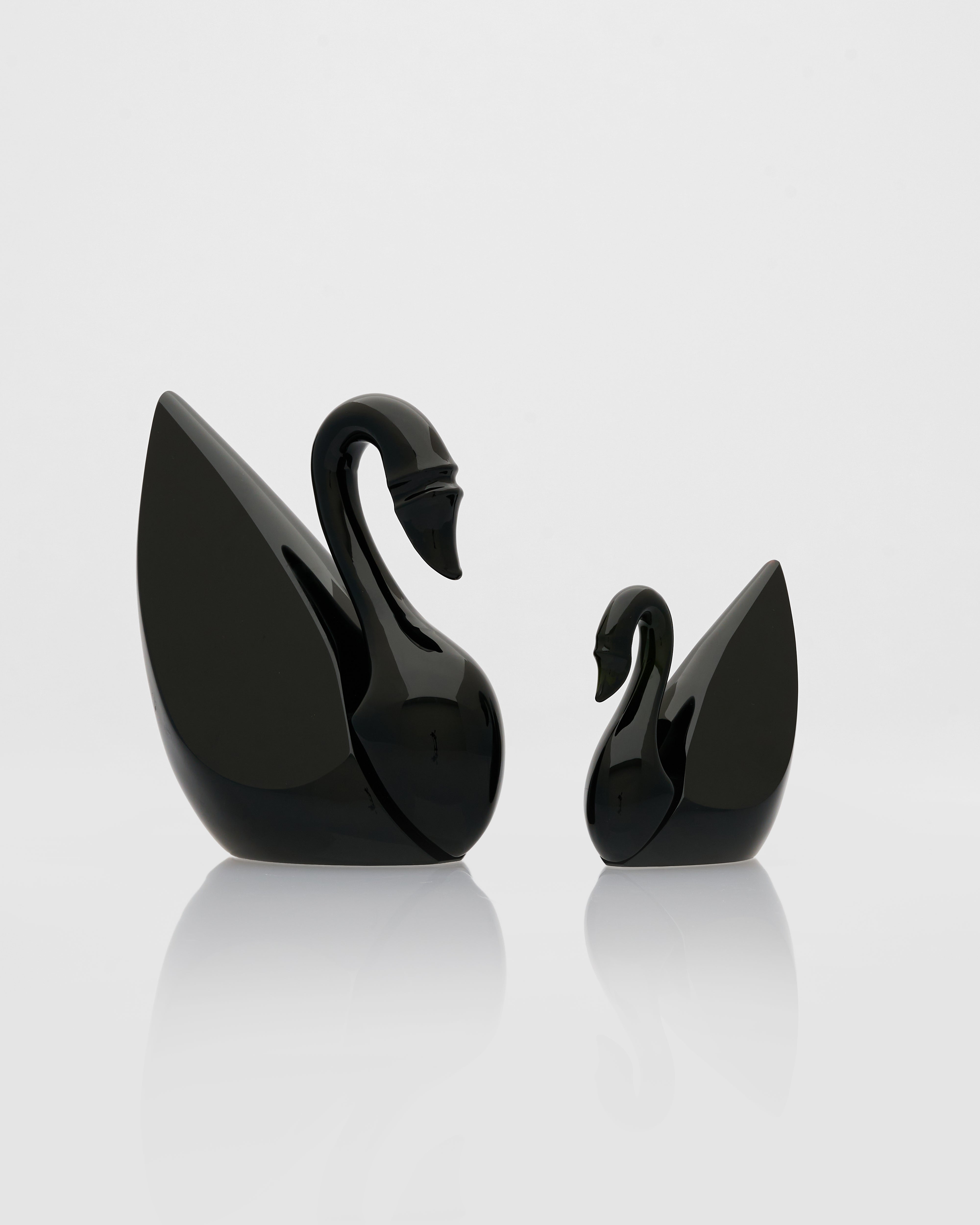 Two black swan-shaped objects on a white background