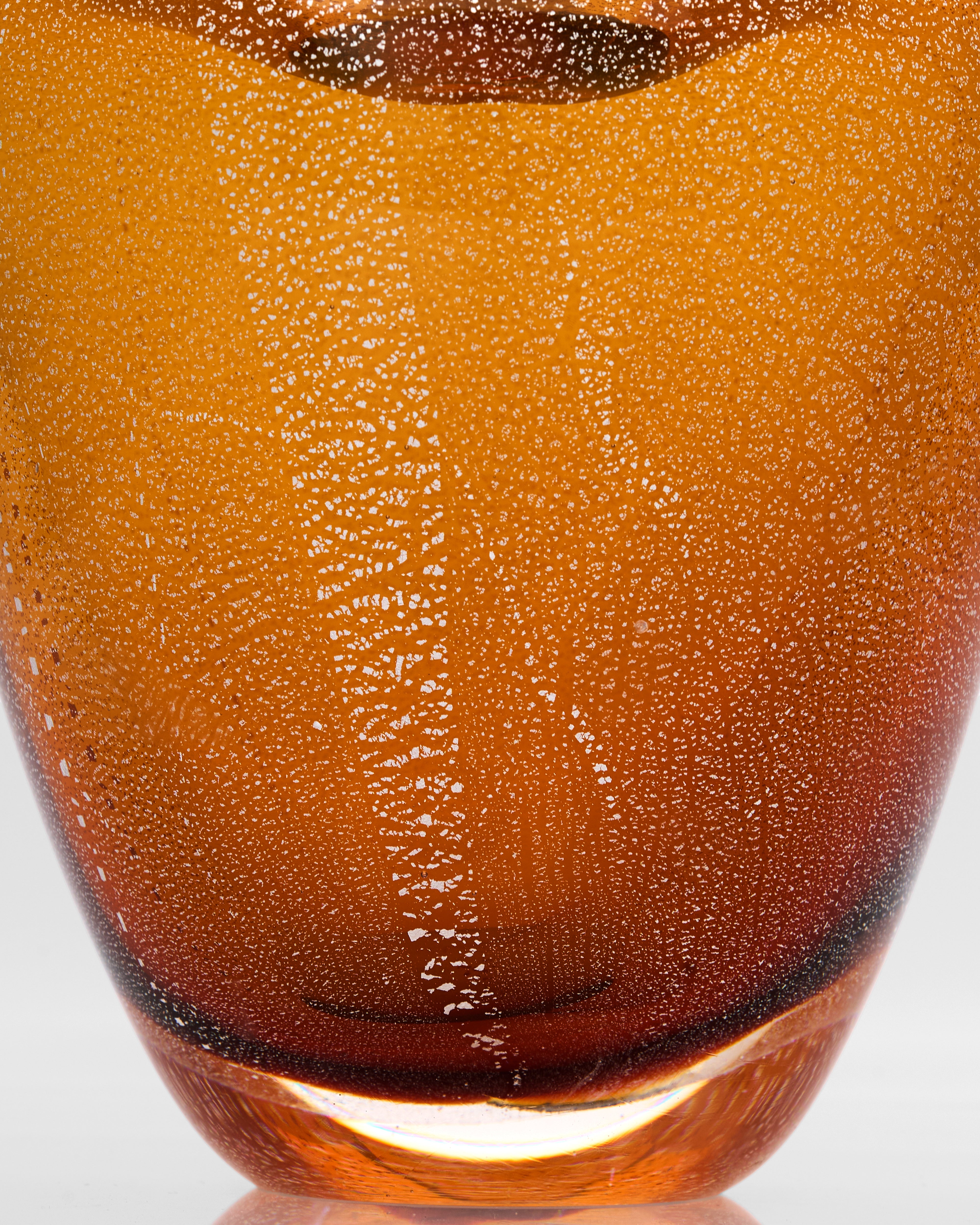 Close-up of a textured amber glass vase on a white background
